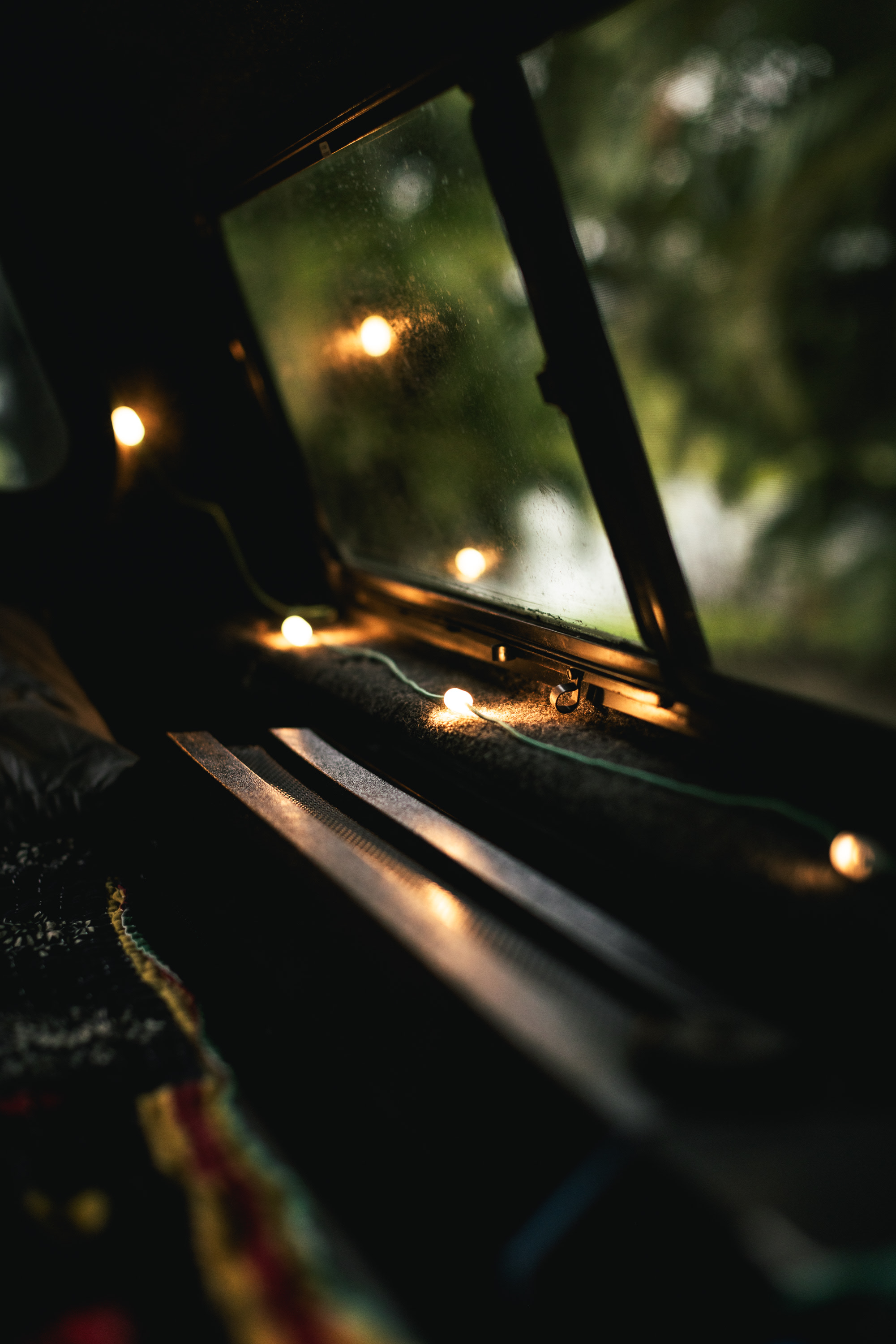 Cozy RV rental interior at night, with string lights illuminating the cabin and a blurred view of nature outside the window.. toyota tacoma 2012