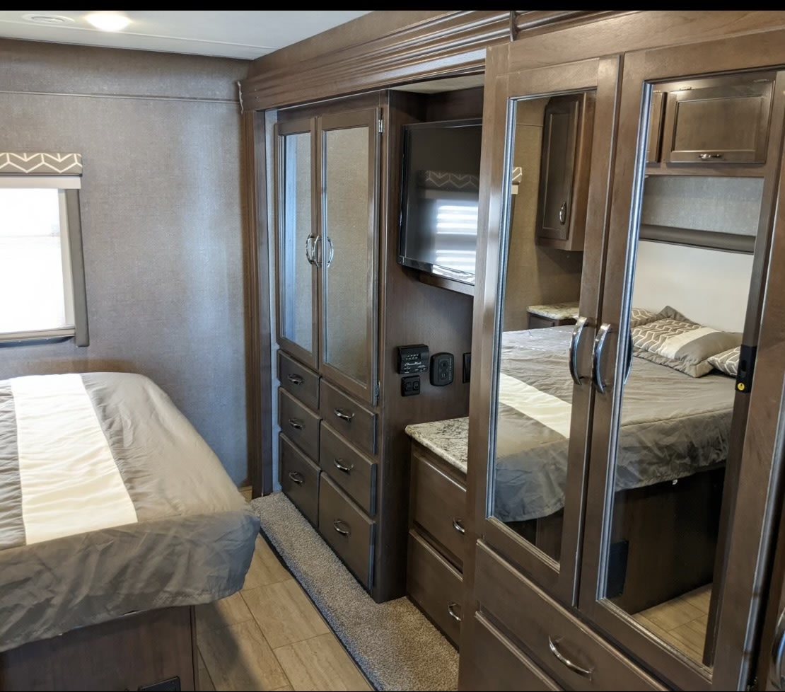Spacious RV rental bedroom featuring modern cabinetry, a mirrored closet, and a comfortable bed. Perfect for your travels.. Ford Freedom Traveler 2019