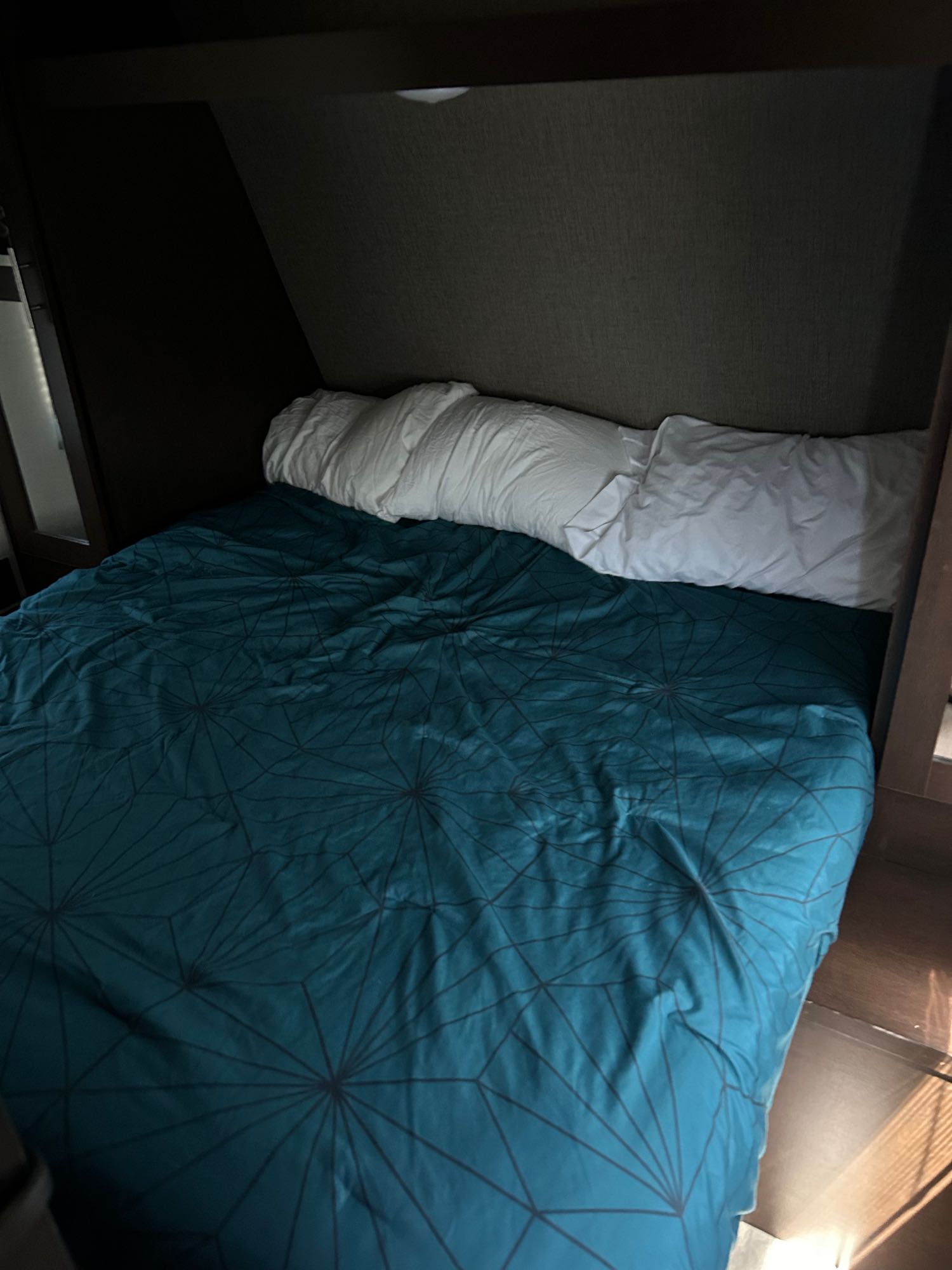 Cozy RV rental bedroom featuring a bed with a teal geometric duvet and white pillows against a dark headboard.. KZ 332BHLE 2018