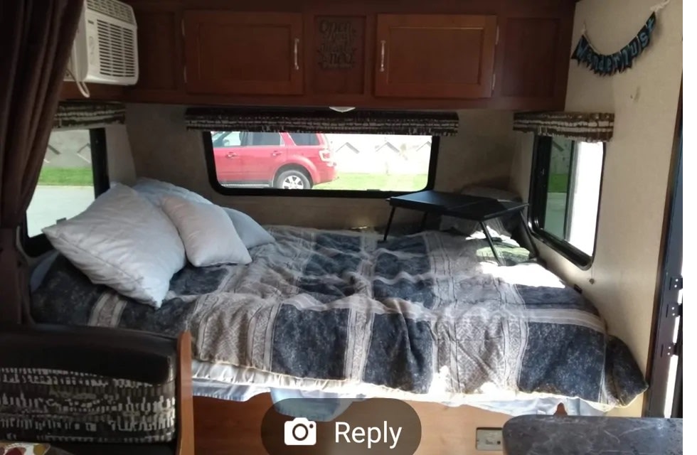 Cozy RV rental interior showing a bed with pillows, an AC unit, and overhead cabinets.. Jayco Jay Flight SLX 2017