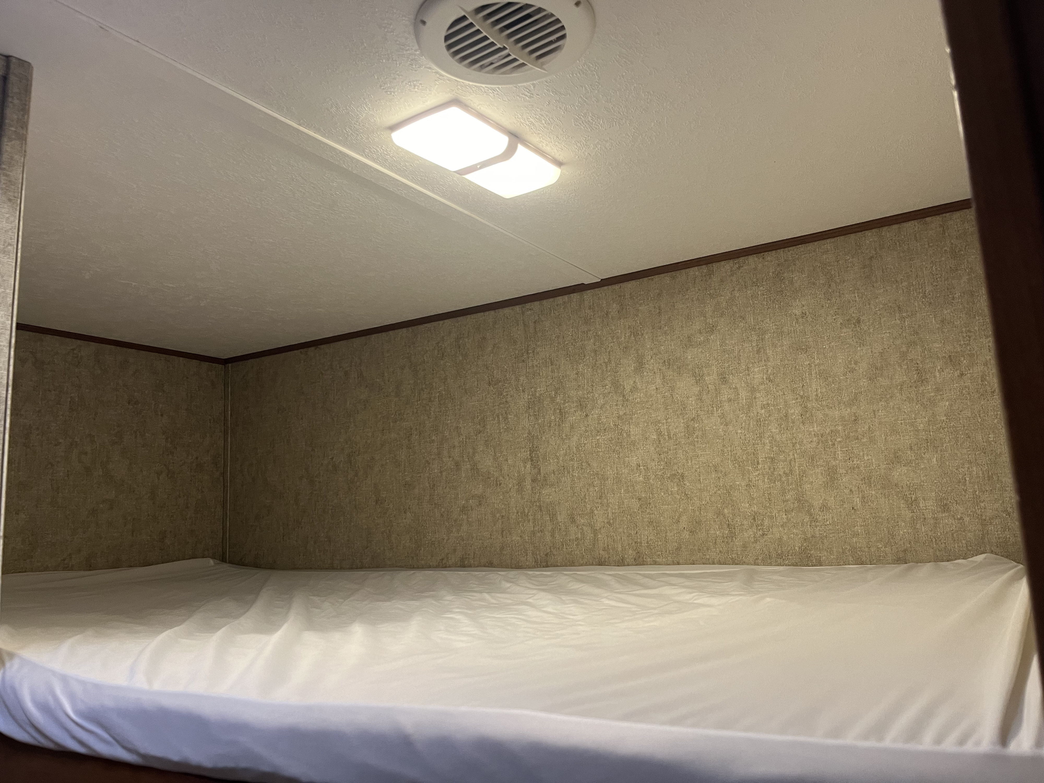 Cozy RV rental bunk bed interior with white mattress, overhead light, and air vent. Ready for your next adventure!. Forest River Avenger 26bh 2018