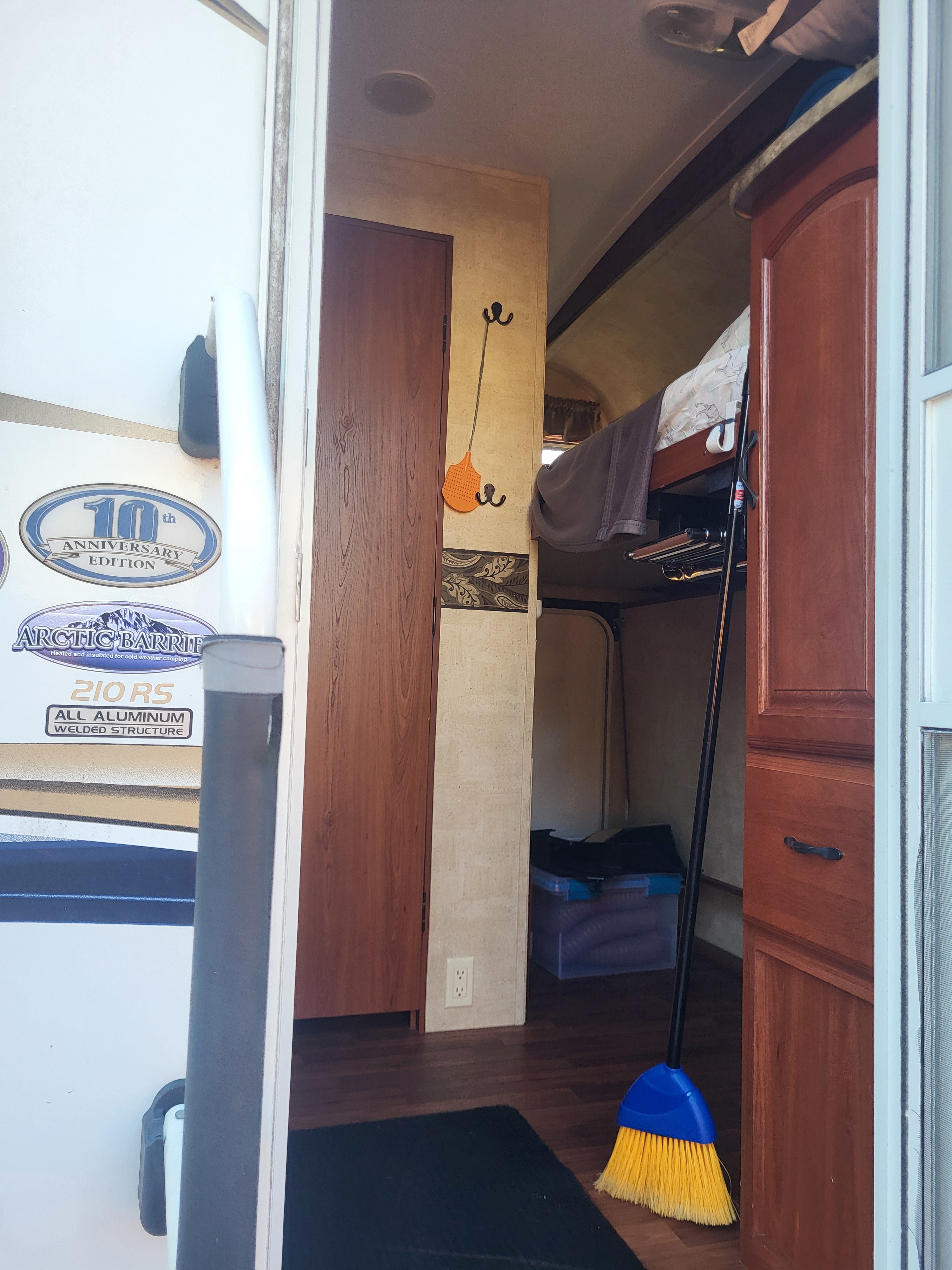 Inside an RV rental: a compact interior with bunk beds, storage, and a broom, designed for insulated cold-weather camping.. Keystone RV Outback 10th Anniversary 2012