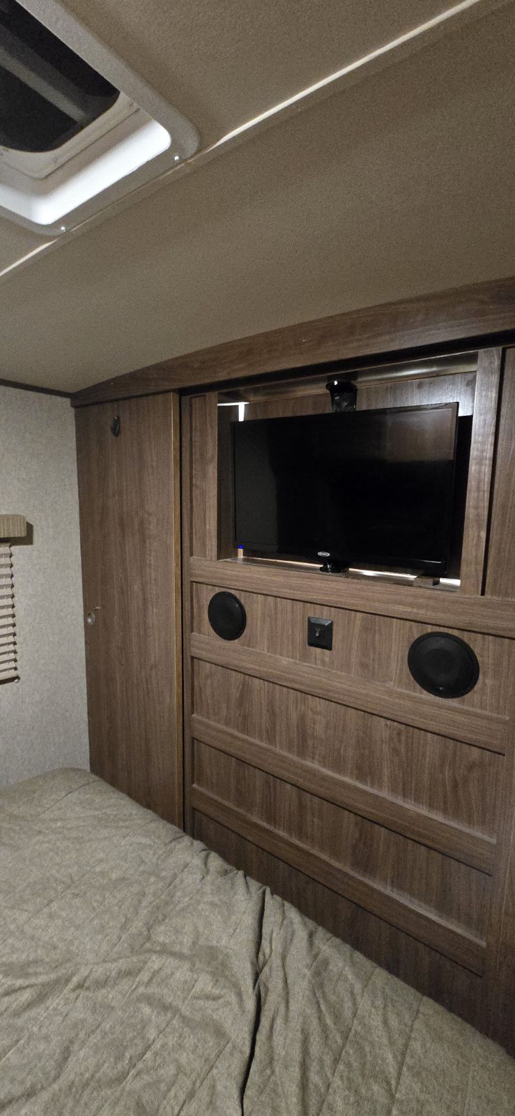 RV rental bedroom with built-in TV, speakers, and bed. A practical and compact interior for travel.. Palomino Solaire 2015