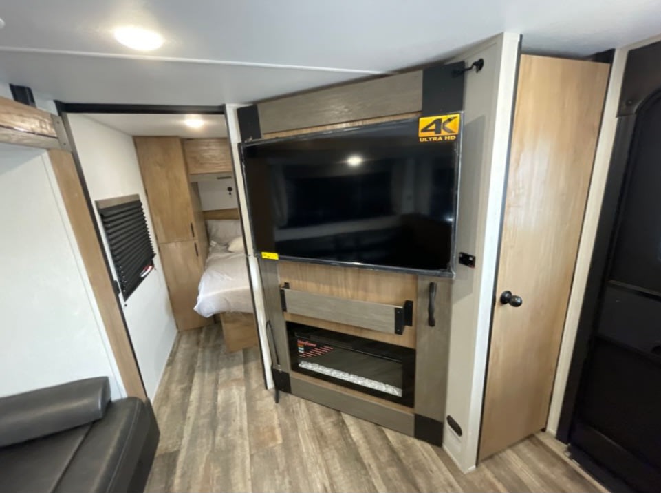 RV rental: Modern compact interior with TV, electric fireplace, and bedroom beyond.. Forest River 5ZT2CRRB2RF077986 2024