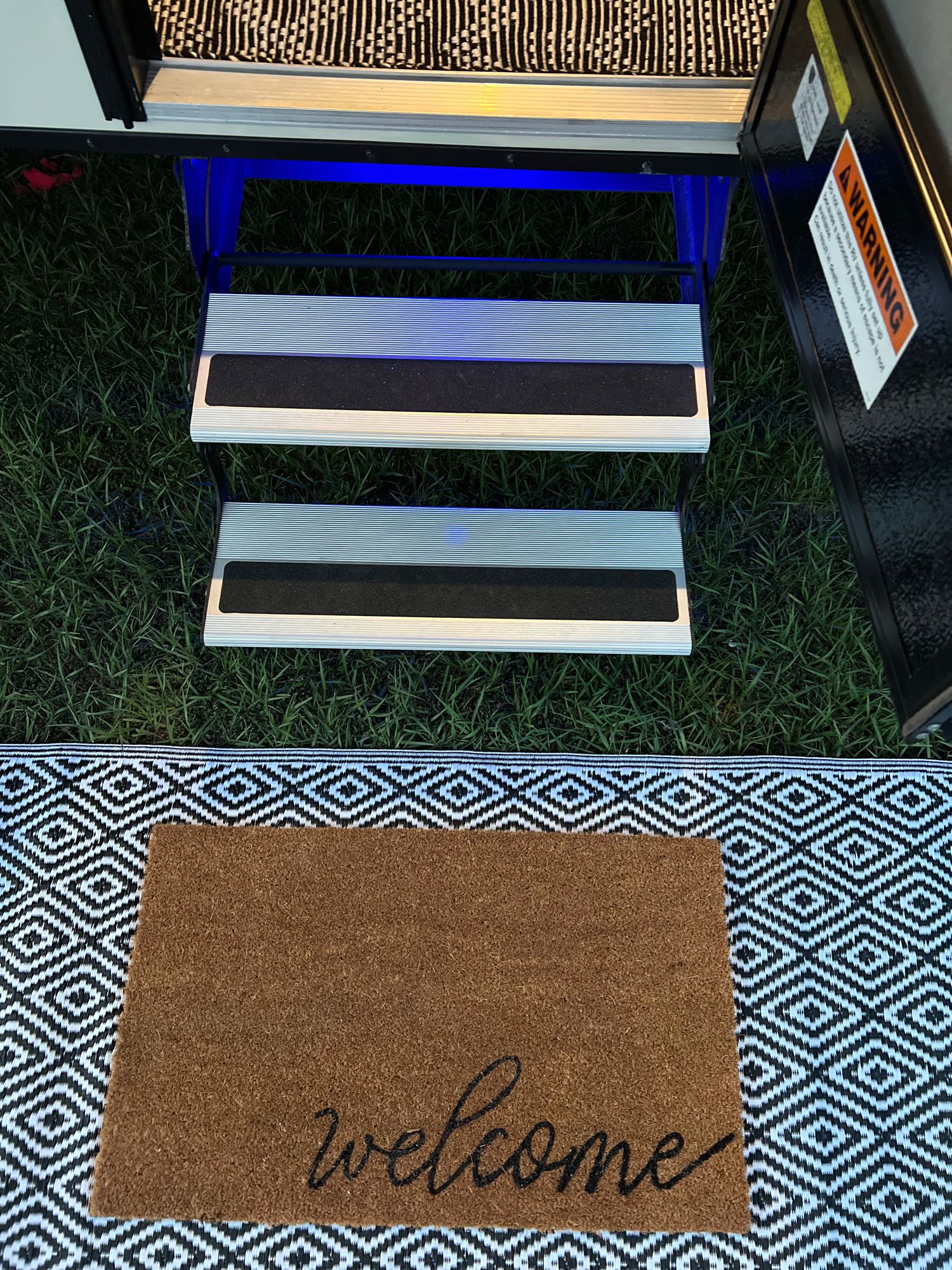 Welcoming RV rental entrance with illuminated steps, green grass, and a decorative mat for guests.. Sonic Sonic Trailer 2019