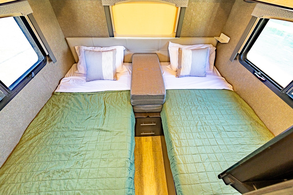 Cozy **RV rental** interior: twin beds with green quilts, pillows, and ample windows for comfortable travel.. Thor Vegas 2018