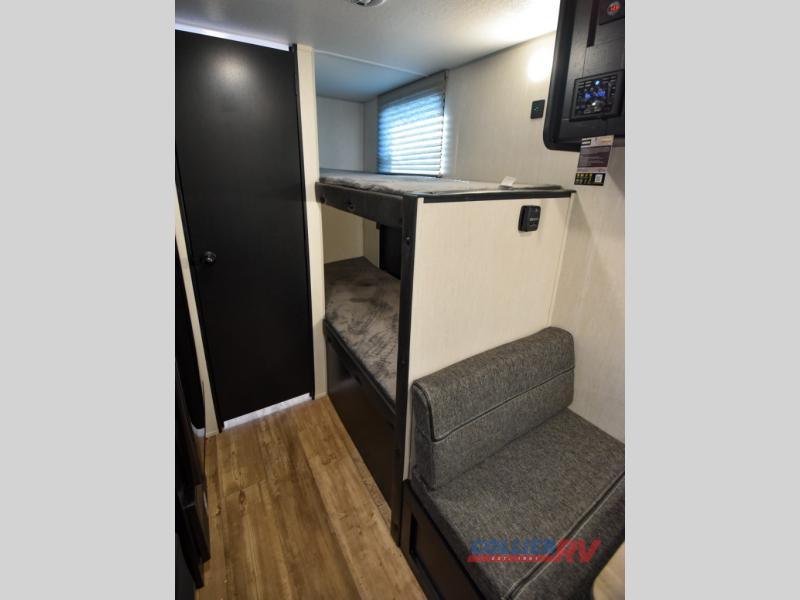RV rental interior: bunk beds, a cozy dinette, wood-look floor, and a door for privacy/storage.. Forest River Cherokee Wolf Pup 2022