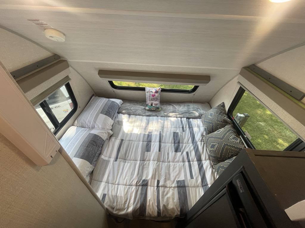 Cozy RV rental sleeping area with striped bed, soft pillows, and side windows providing natural light.. R-Pod R-Pod Trailer 2023