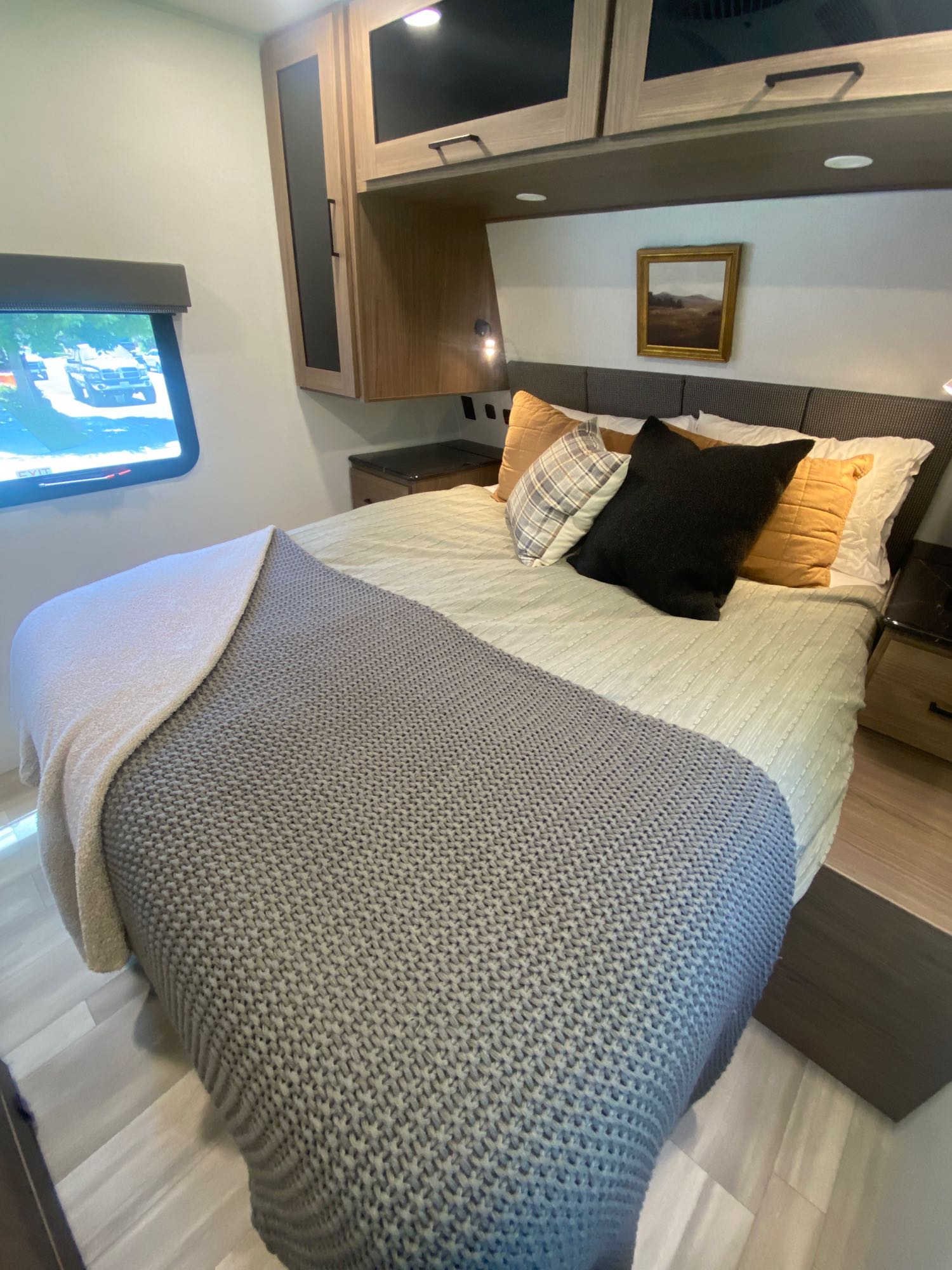 Inviting RV rental bedroom with a comfortable bed, overhead cabinets, wall-mounted TV, and cozy blankets.. Alliance Delta 251BH 2024