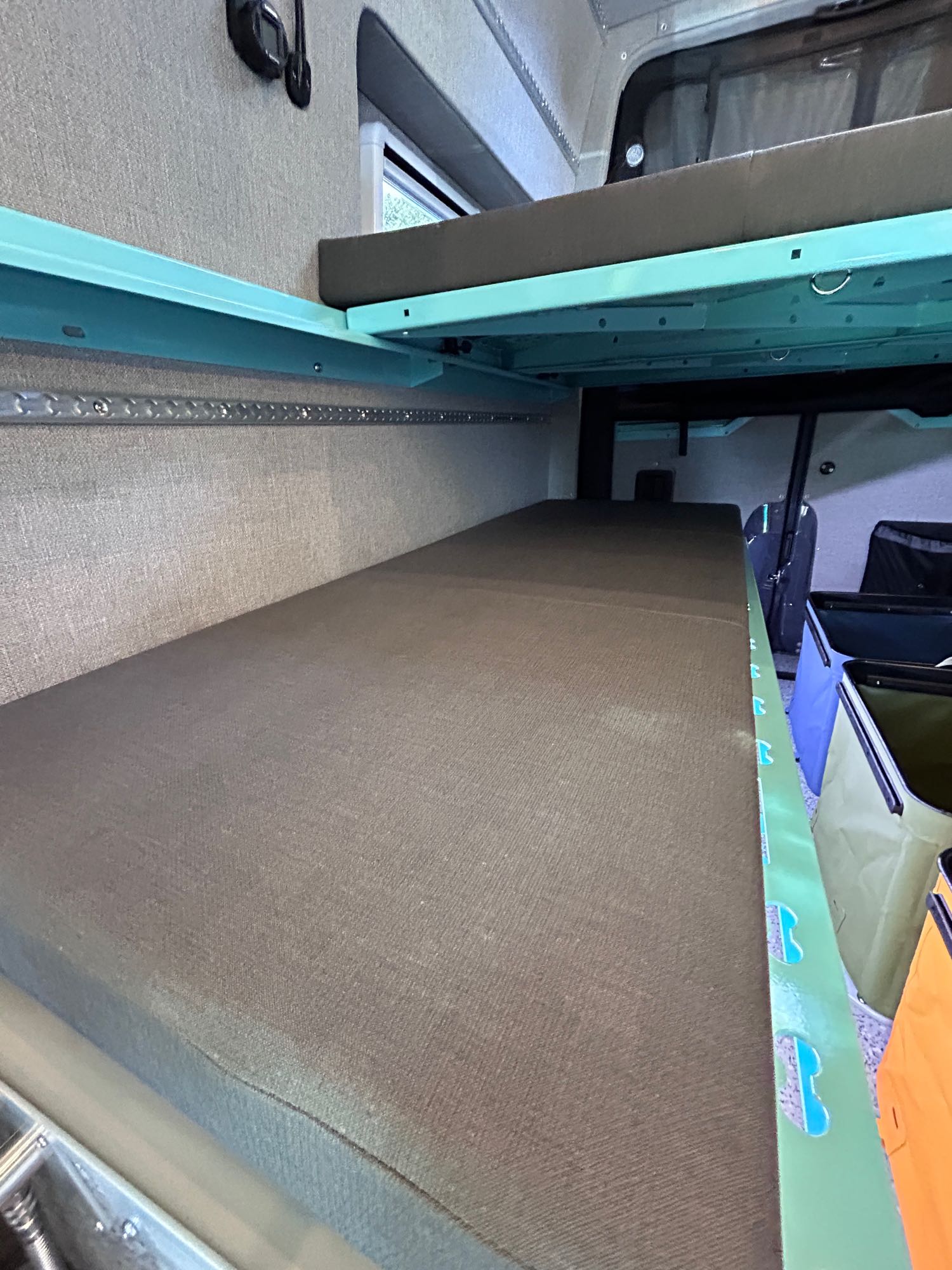 RV rental interior features stacked bunk beds with teal frames and fabric walls, providing compact sleeping space for trips.. Mercedes sprinter 2500 170 AWD 2024