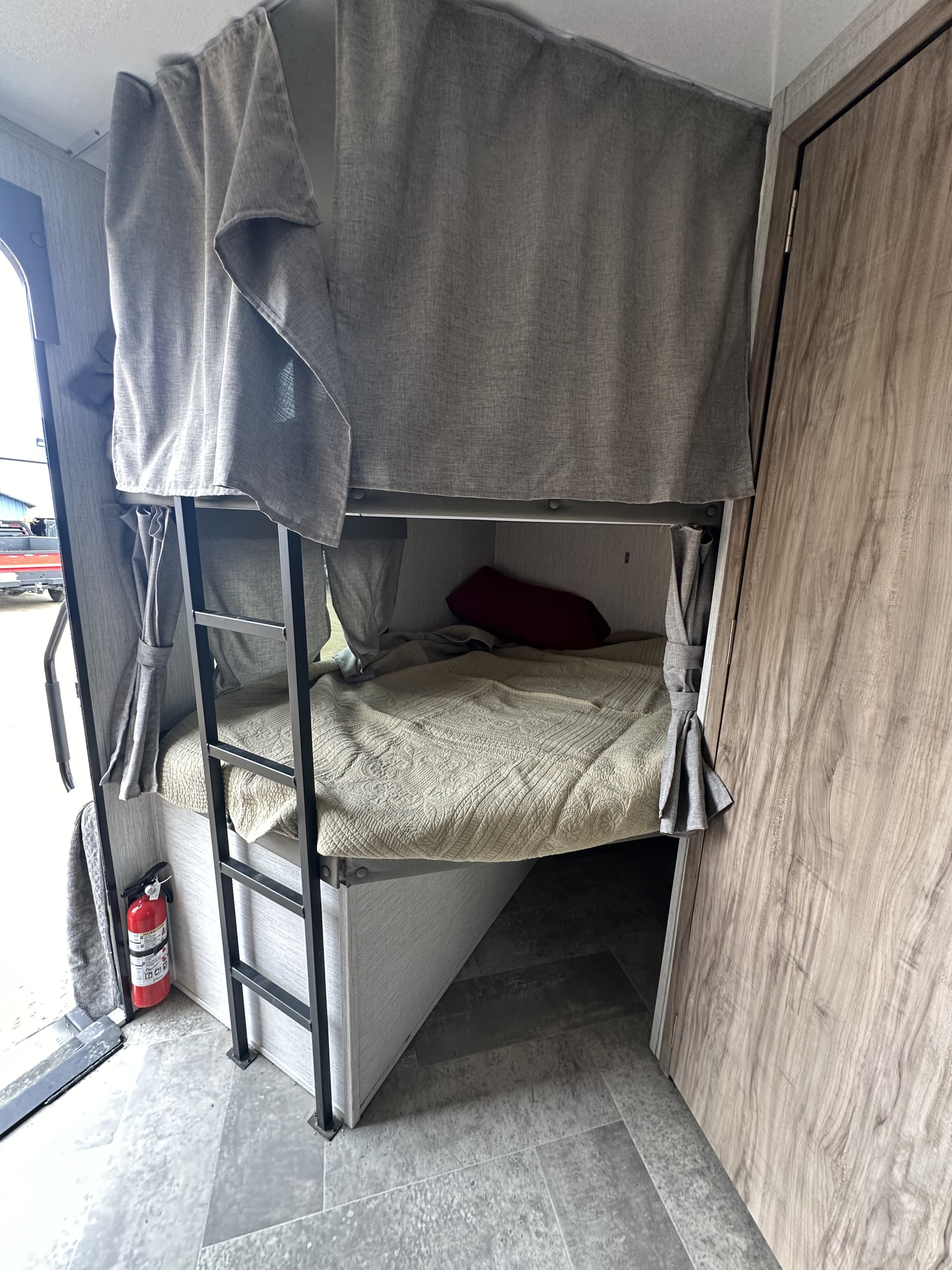 Cozy RV rental bunk beds with privacy curtains, ladder, and a visible fire extinguisher for safety.. Palomino Solaire Ultra Lite 243BHS 2022