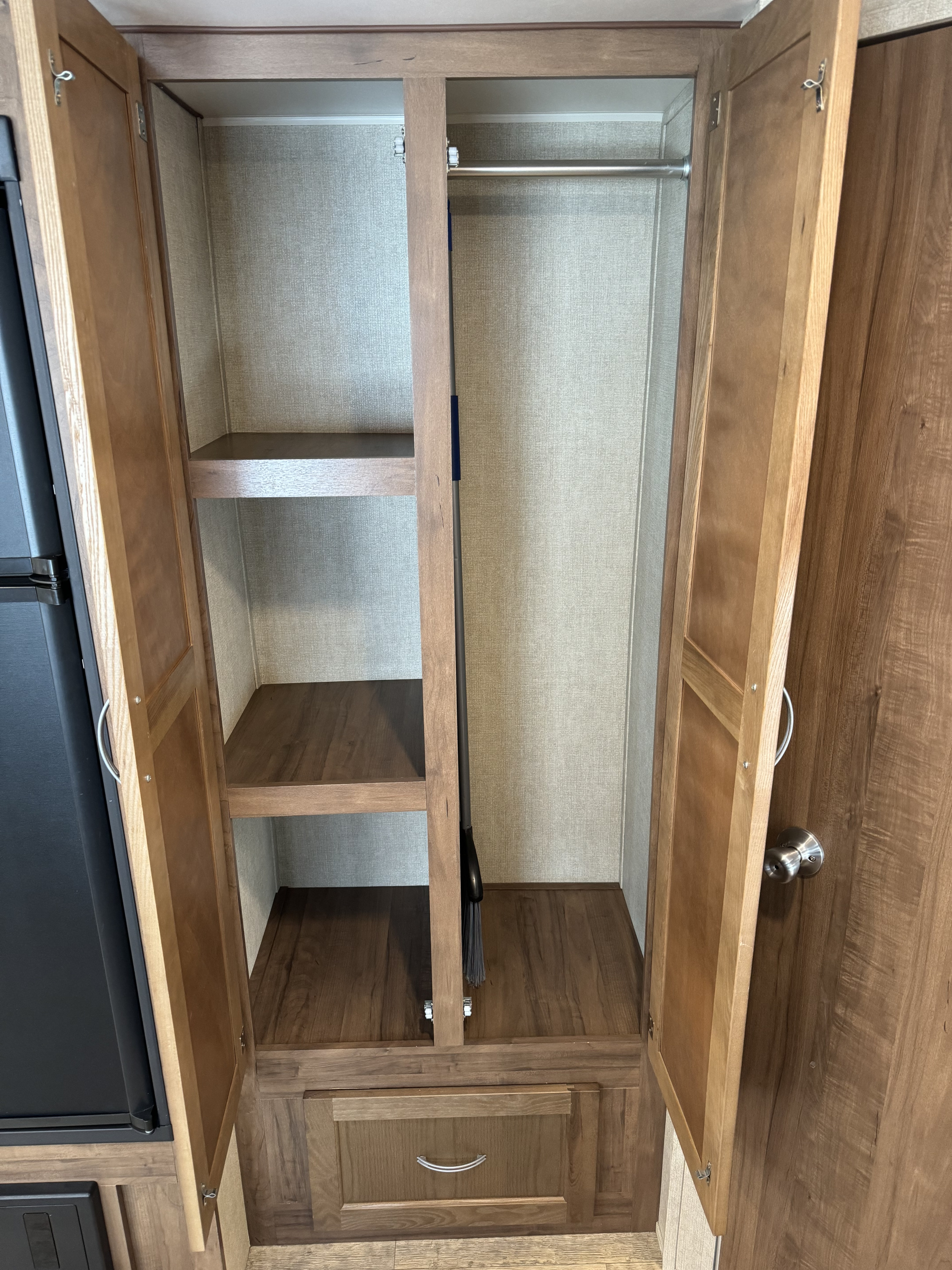 Inside an RV rental: a versatile wardrobe with a hanging rod, shelves, and even a broom, perfect for organized RV living.. Gulf Stream Ameri-Lite 2018