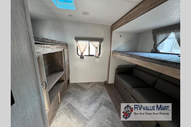 RV rental interior features bunk beds, a comfy sofa, and storage, all on herringbone flooring. Ideal for family camping.. Forest River Palomino Solaire 2023