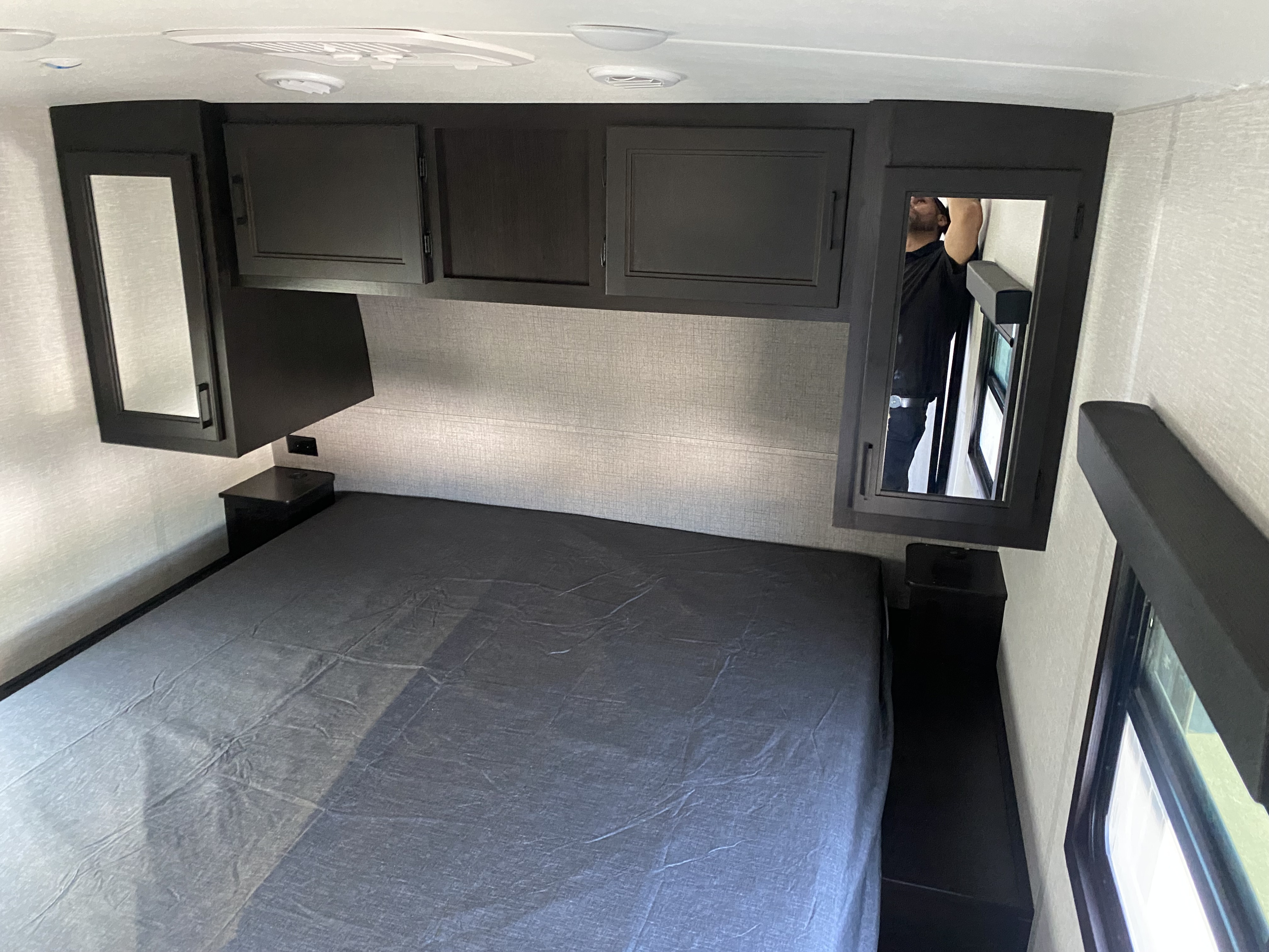 RV rental interior: a clean, compact bedroom with dark cabinetry, nightstands, and a covered bed.. Highland Ridge RV Open Range Lite 2023