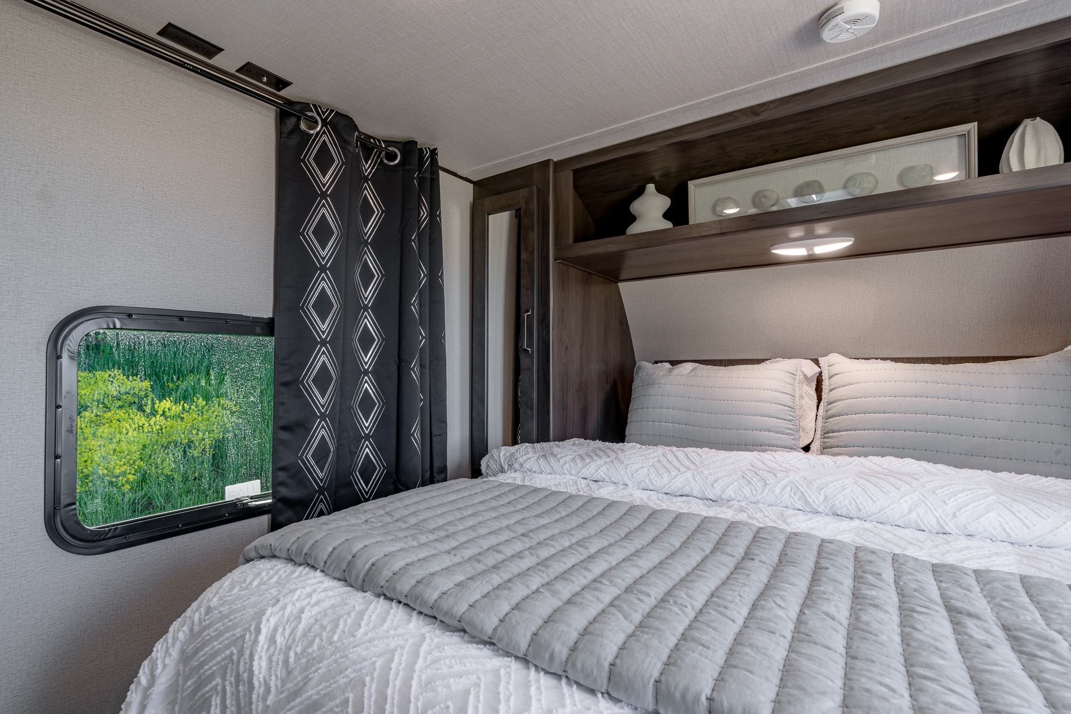 This RV rental offers a well-appointed bedroom with a comfy bed, storage, and a scenic window view of nature.. Grand Design Transcend Xplor 2021