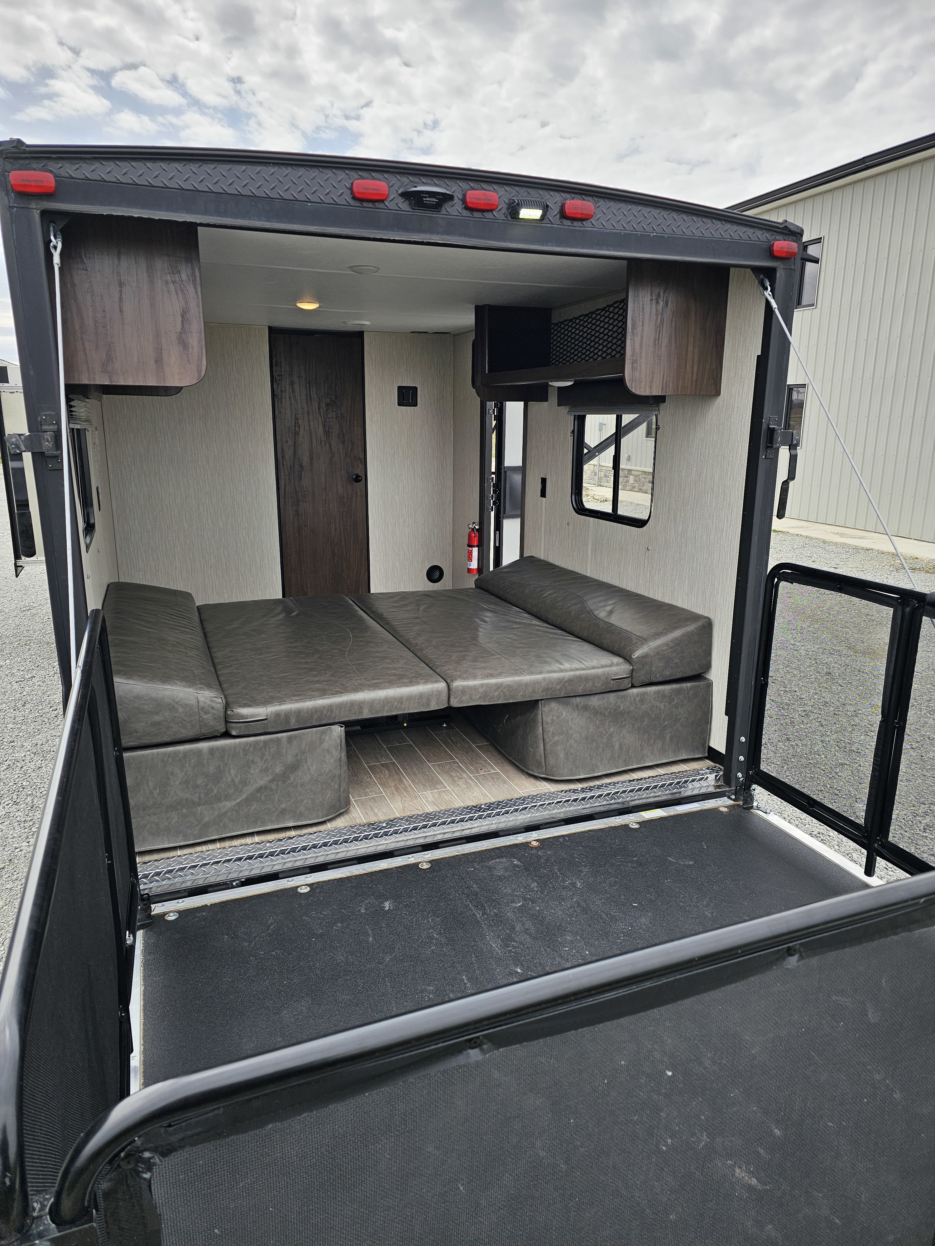 Explore this RV rental's versatile toy hauler interior, featuring convertible gray seating, wood flooring, and an open rear ramp.. Forest River Cherokee Grey Wolf 2021