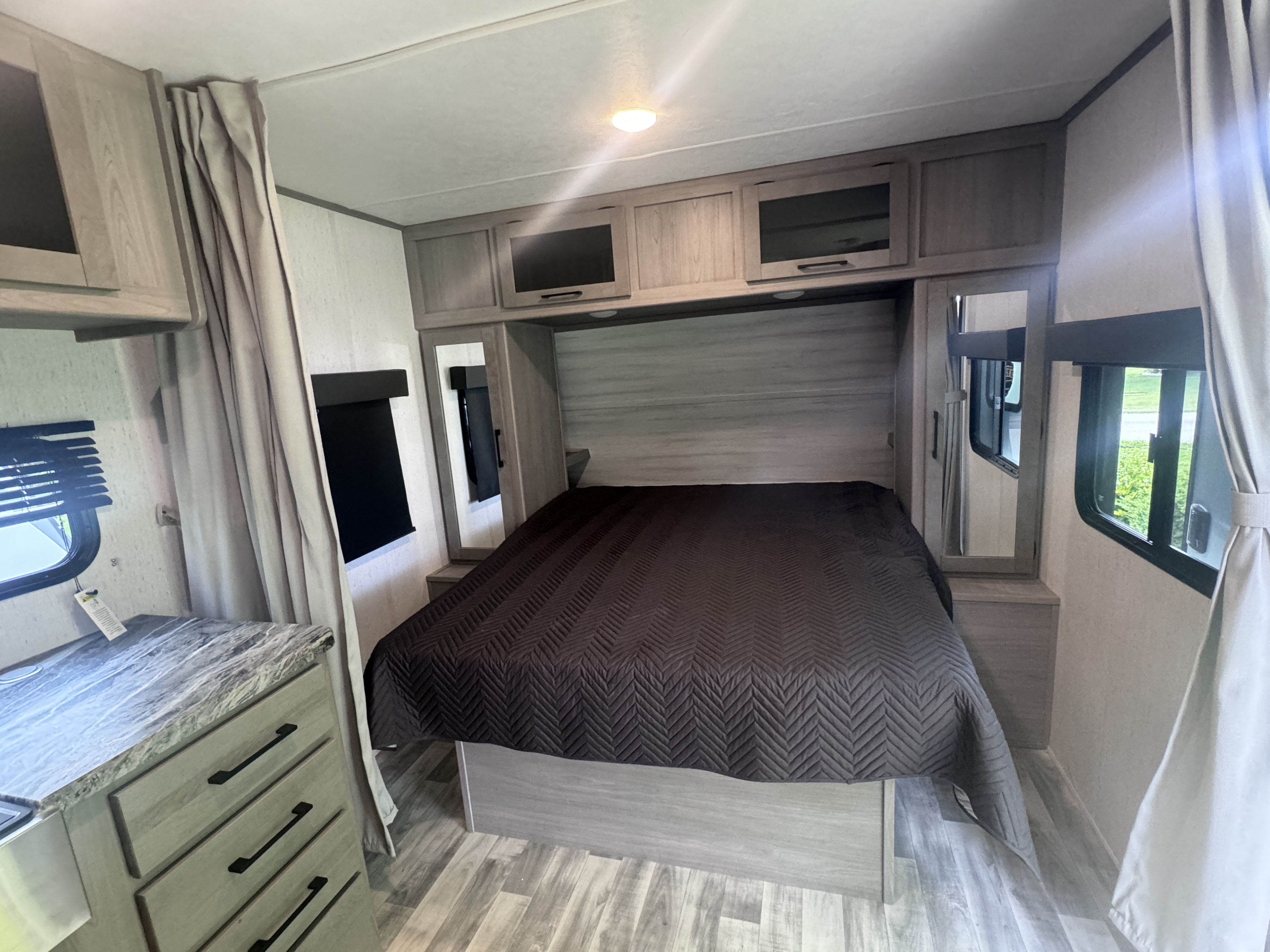 Experience comfort in this RV rental's compact bedroom, featuring a large bed, overhead cabinets, and bright interior.. Dutchmen Kodiak Ultra Lite 2022