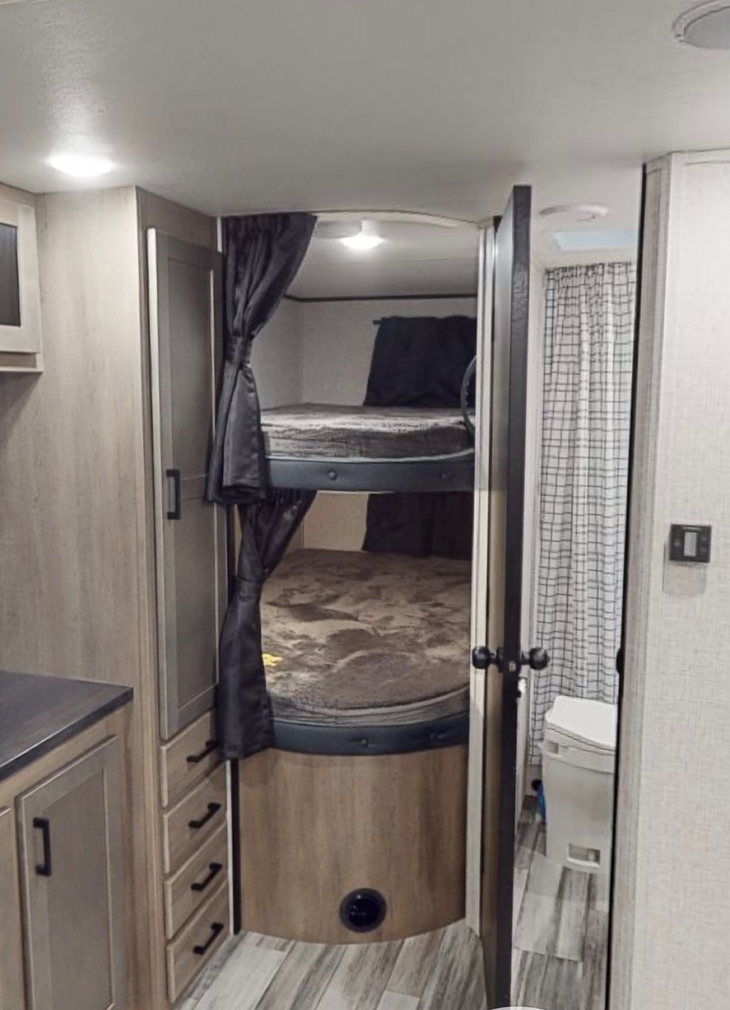 Cozy RV rental interior featuring bunk beds with privacy curtains, built-in cabinetry, and a compact bathroom. Ready for adventure!. Jayco Jayflight 2024