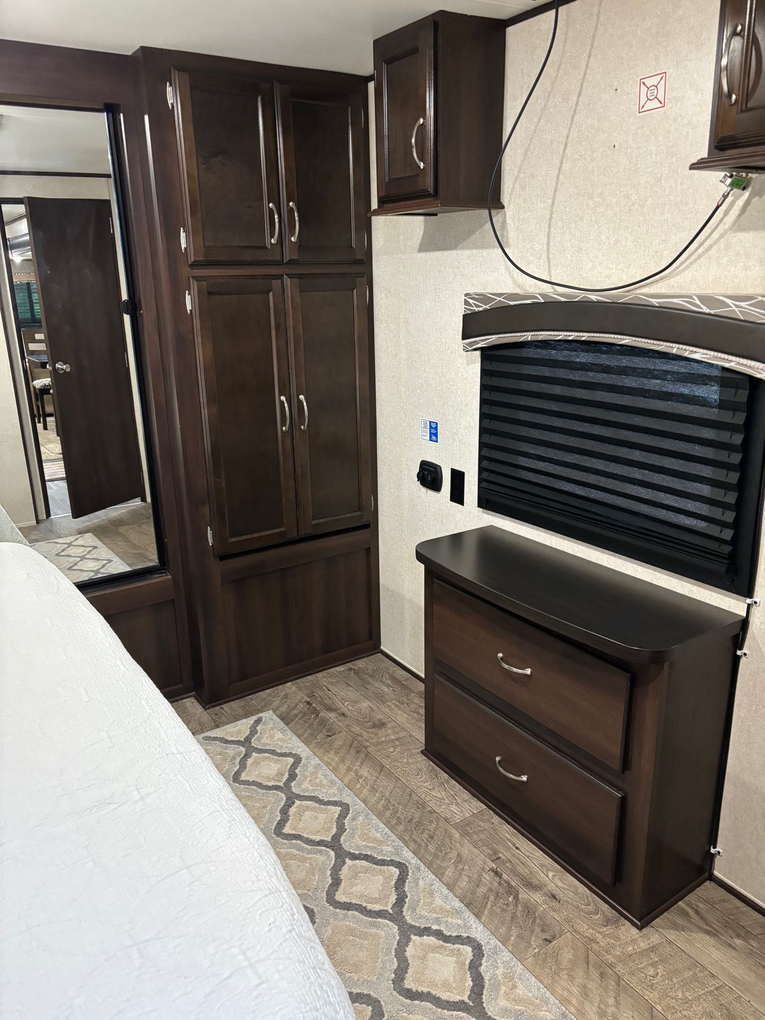 RV rental bedroom with dark wood cabinetry, dresser, and bed. Efficient, organized space for comfortable RV travel.. Jayco Jay Flight 2018
