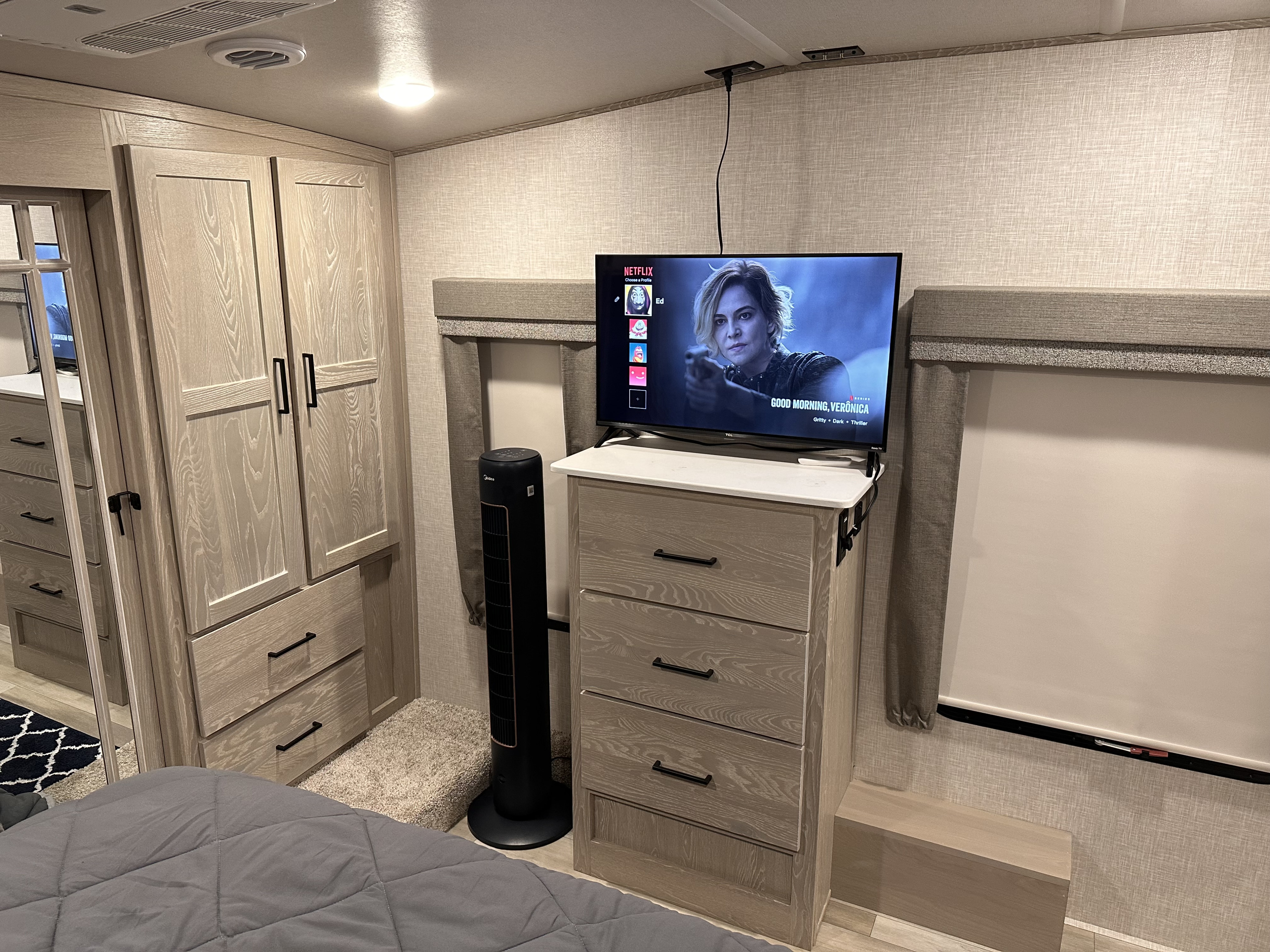 RV rental bedroom featuring a dresser, TV, and built-in wardrobe. Practical, compact living space with light wood finishes.. Forest River Flagstaff Classic 2023