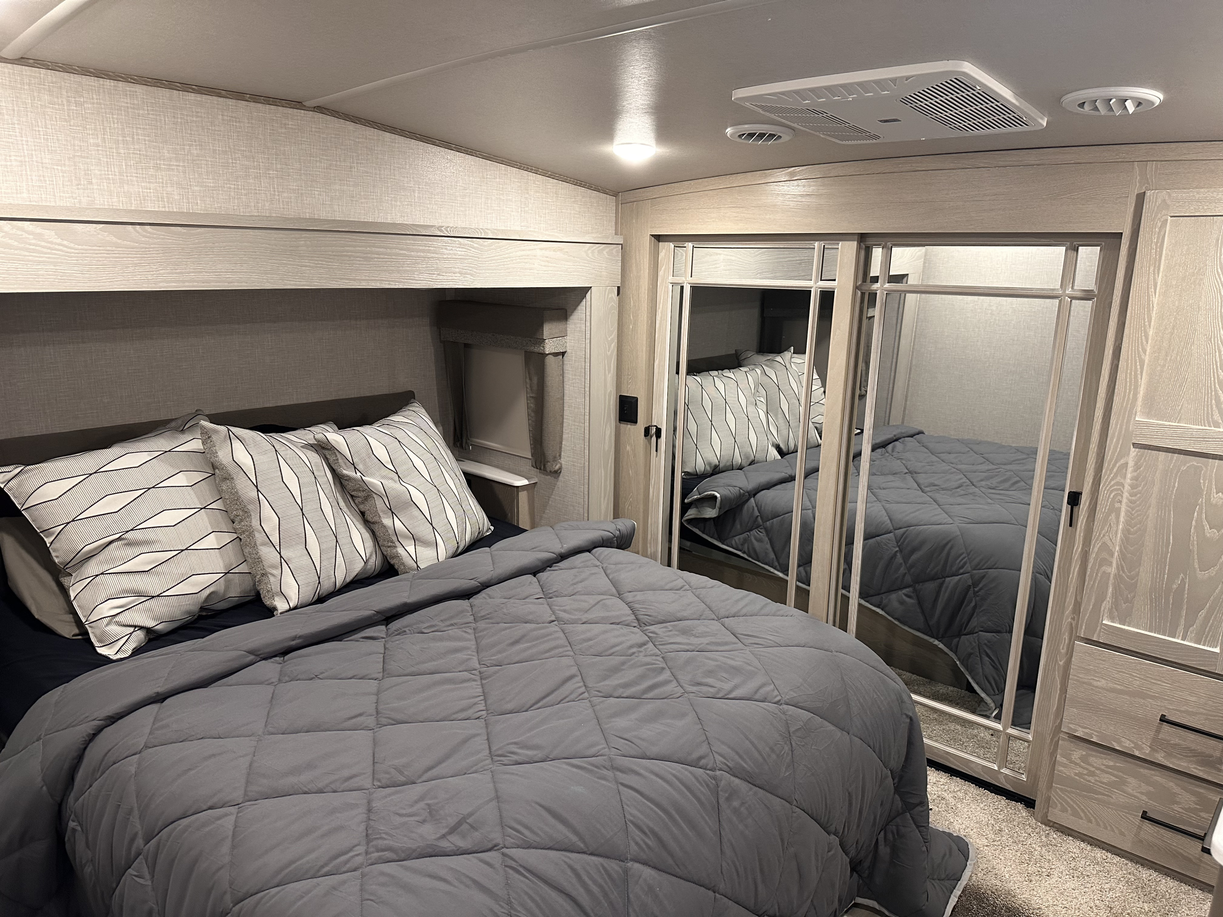 Cozy modern RV rental bedroom with gray bedding, mirrored closet, and wood-look finishes.. Forest River Flagstaff Classic 2023