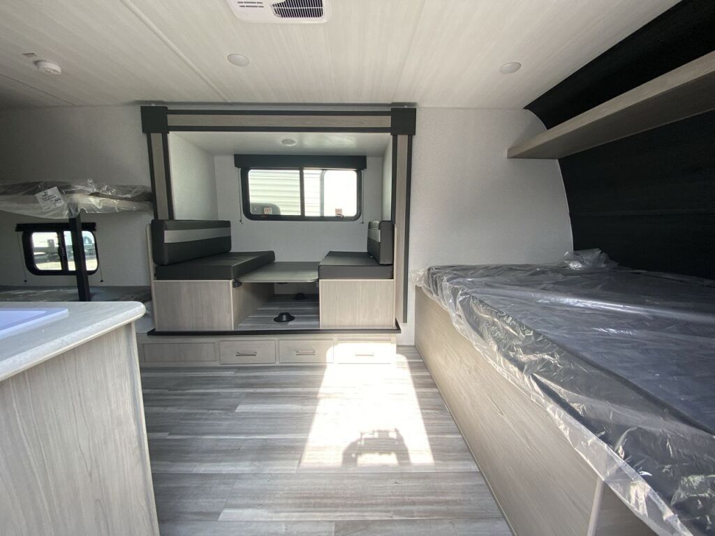 Spacious RV rental interior featuring bunk beds, a wrapped main bed, and a dinette area, perfect for travel.. Keystone RV Springdale 2024