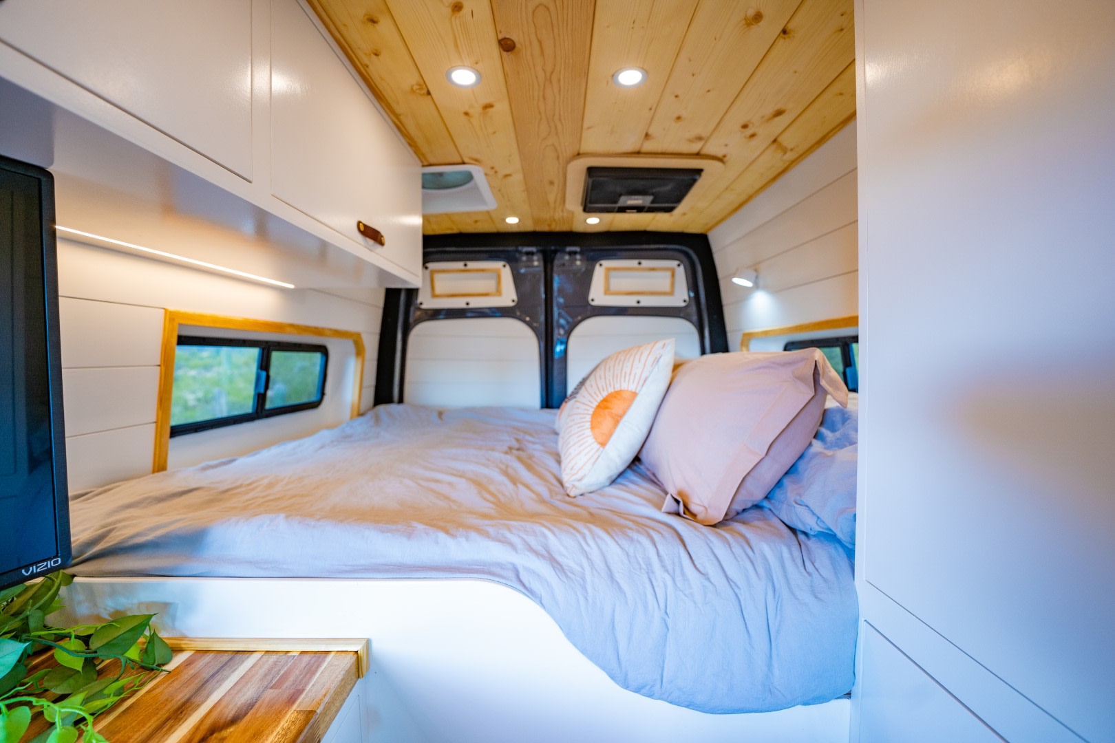 Inviting RV rental interior: a soft bed, wooden ceiling, bright lighting, and built-in storage for mobile adventures.. Mercedes-Benz Sprinter 2023