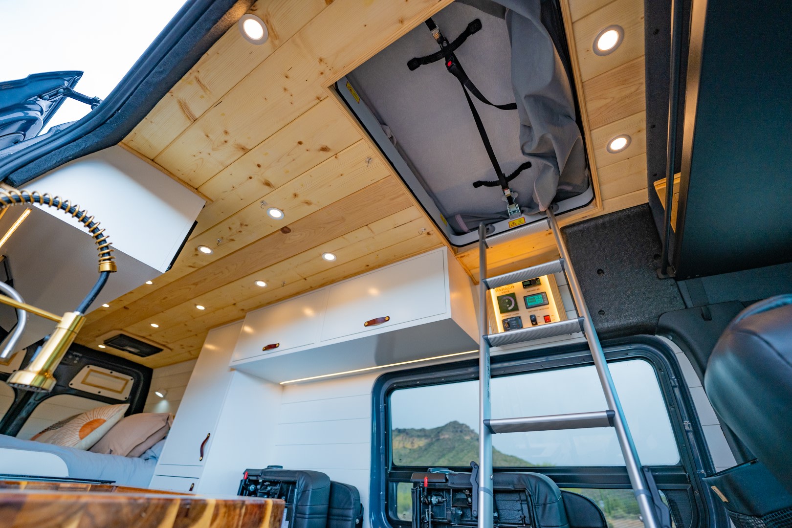 This RV rental offers a custom interior: wood ceiling, modern kitchenette, control panel, and ladder to an upper bunk.. Mercedes-Benz Sprinter 2023