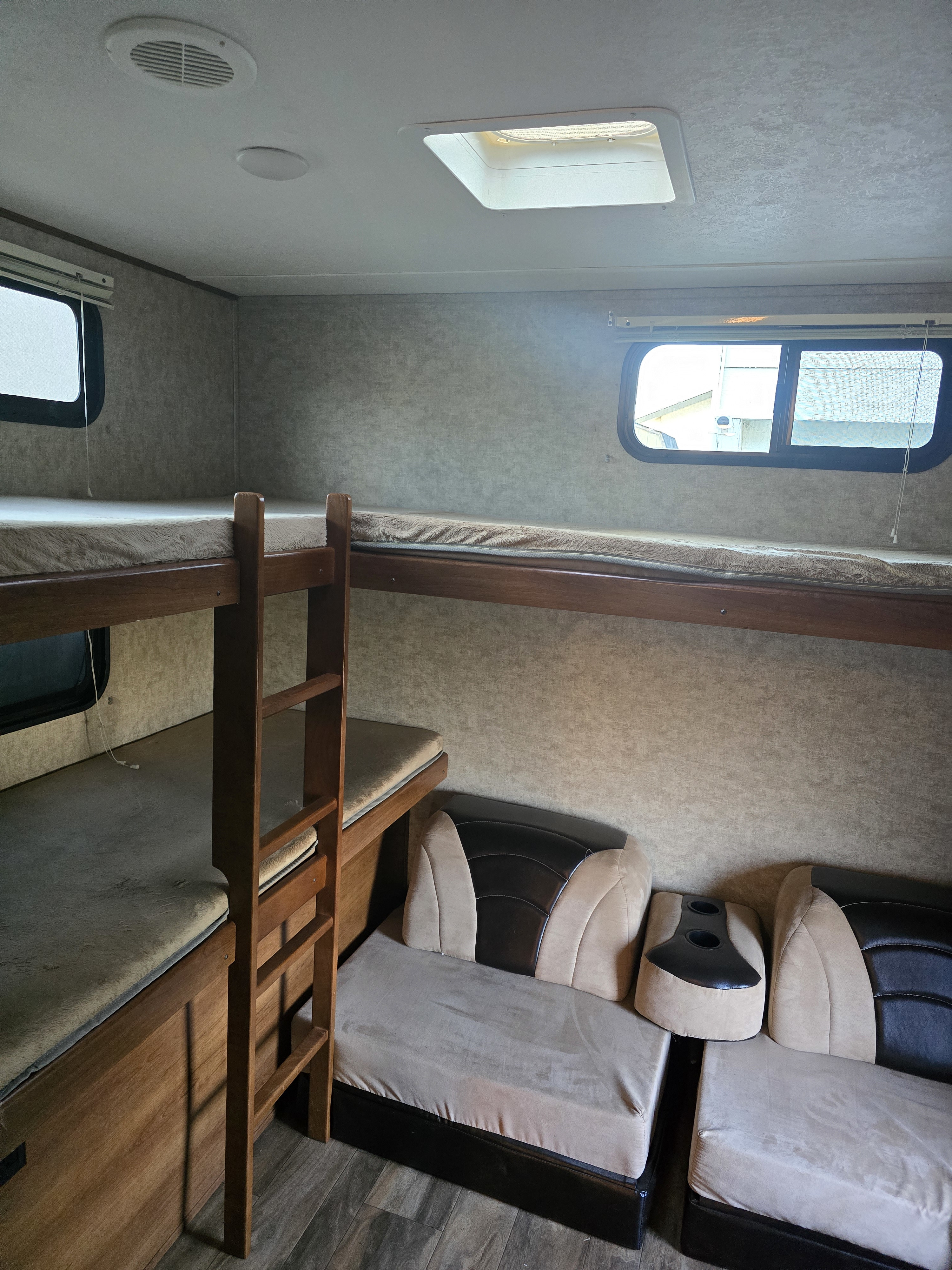 This RV rental interior features bunk beds, a sofa with cup holders, ceiling vent, and skylight.. Forest River Tracer Air 2017