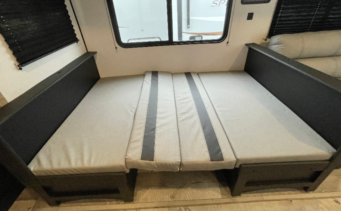 RV rental interior: A versatile dinette converts into a comfortable bed with light gray cushions, ideal for sleeping.. Keystone RV Springdale 2021
