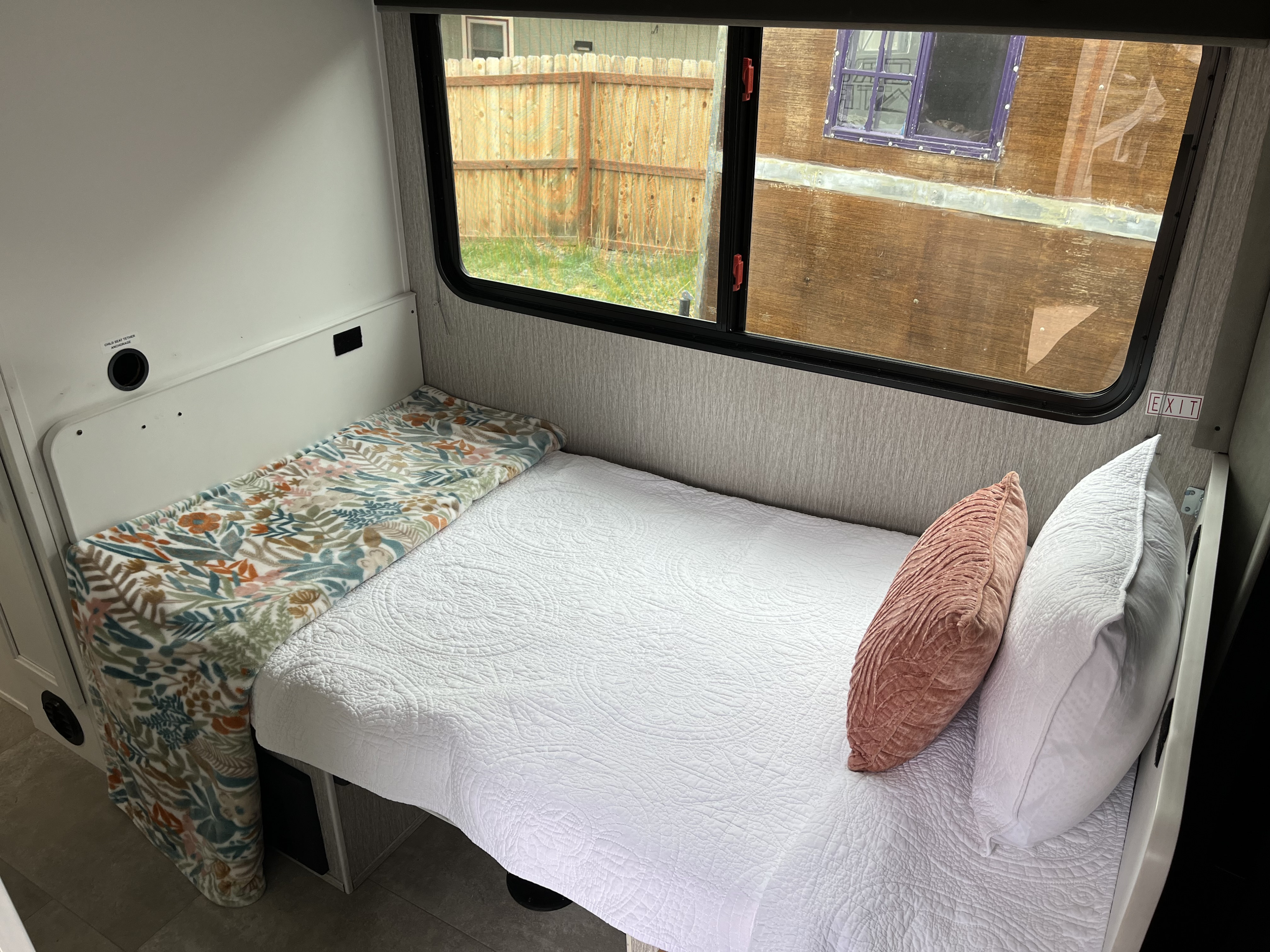Cozy RV rental interior with a comfortable bed, floral blanket, and large windows. Ideal for a relaxing adventure.. Coachmen Cross Trail 2022