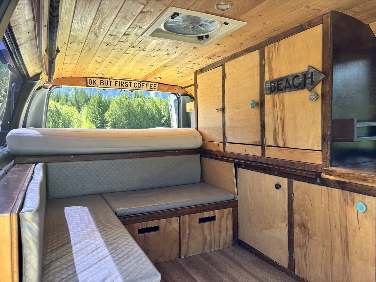Cozy custom RV rental interior with wooden accents, built-in storage, and a view of nature. Perfect for travel adventures!. Ford Ford E350 1996