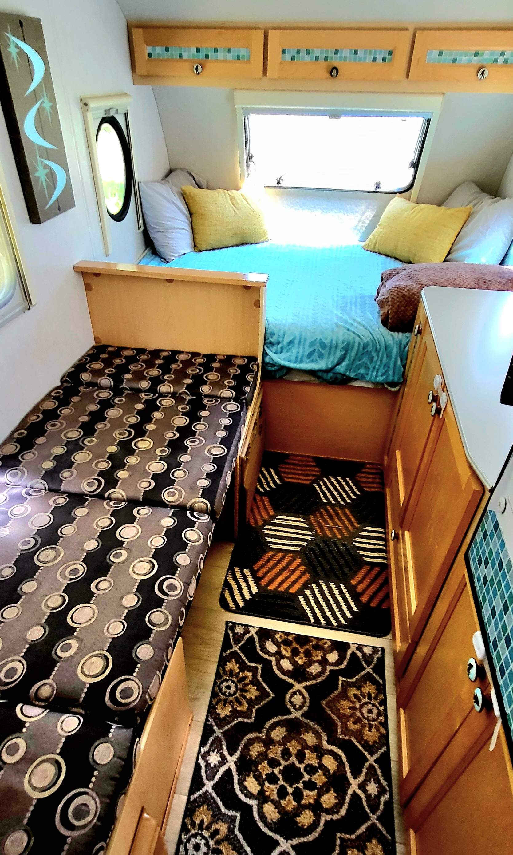 Cozy RV rental interior with bed, bench, and decorative rugs. Perfect for travel adventures!. Dutchmen T@da 2009