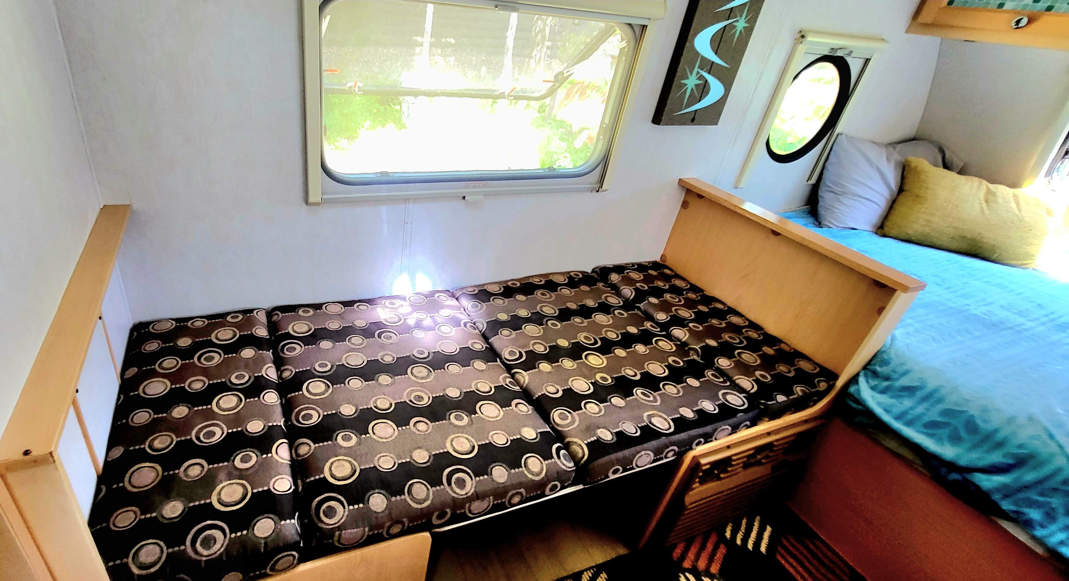 Cozy RV rental interior featuring a versatile sofa bed and an additional sleeping area with blue bedding.. Dutchmen T@da 2009