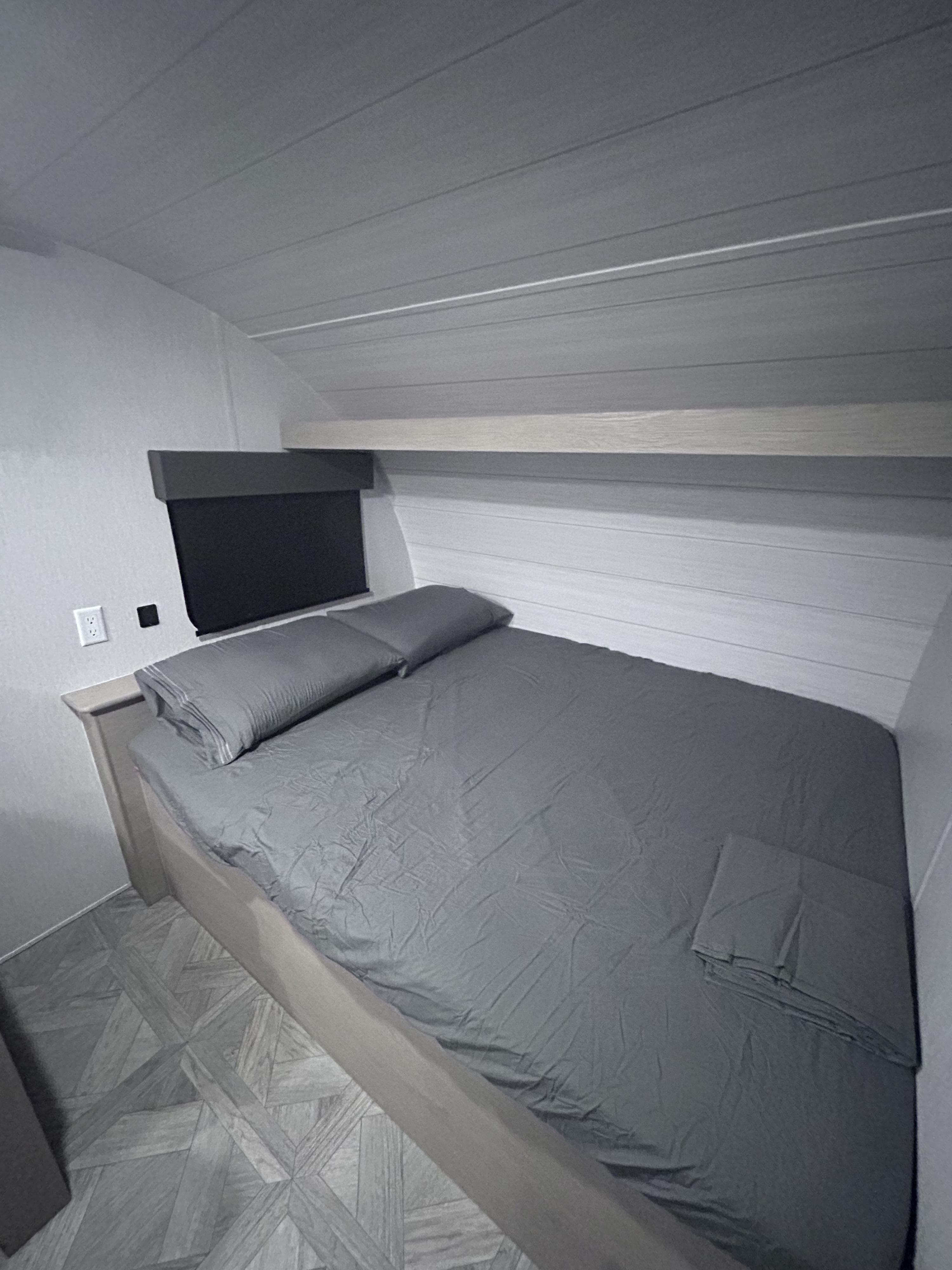 RV rental bedroom features a cozy grey bed, wall paneling, and wood-look flooring. Ideal for travel comfort.. Forest River Salem Cruise Lite 2024