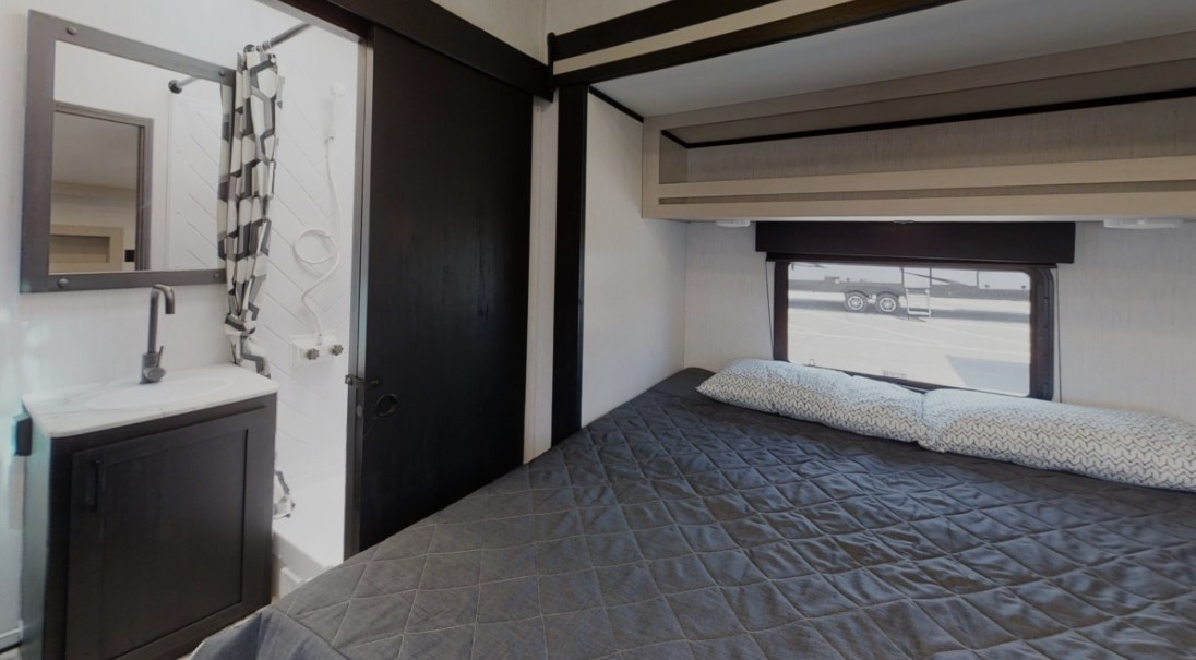 This RV rental features a cozy bedroom with a large bed, window, and overhead storage, plus a compact bathroom with a sink and shower.. Heartland RVs Fuel Toy Hauler 2021