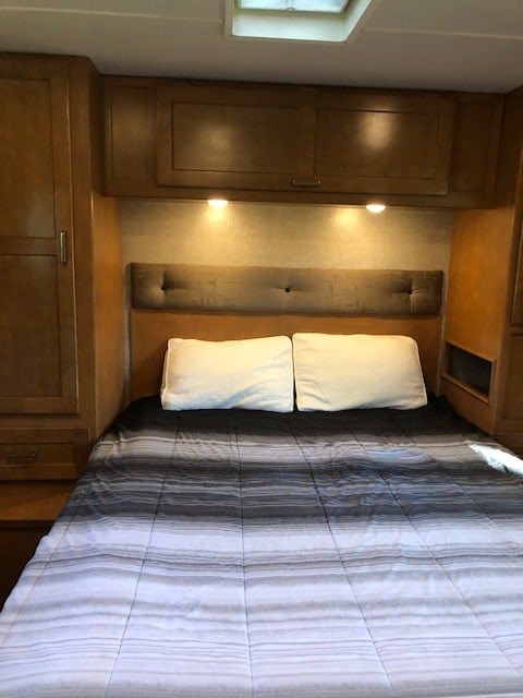 Sleep soundly in this RV rental's bedroom. Features a comfortable bed, padded headboard, & ample overhead storage.. Winnebago Minnie Winnie 2019