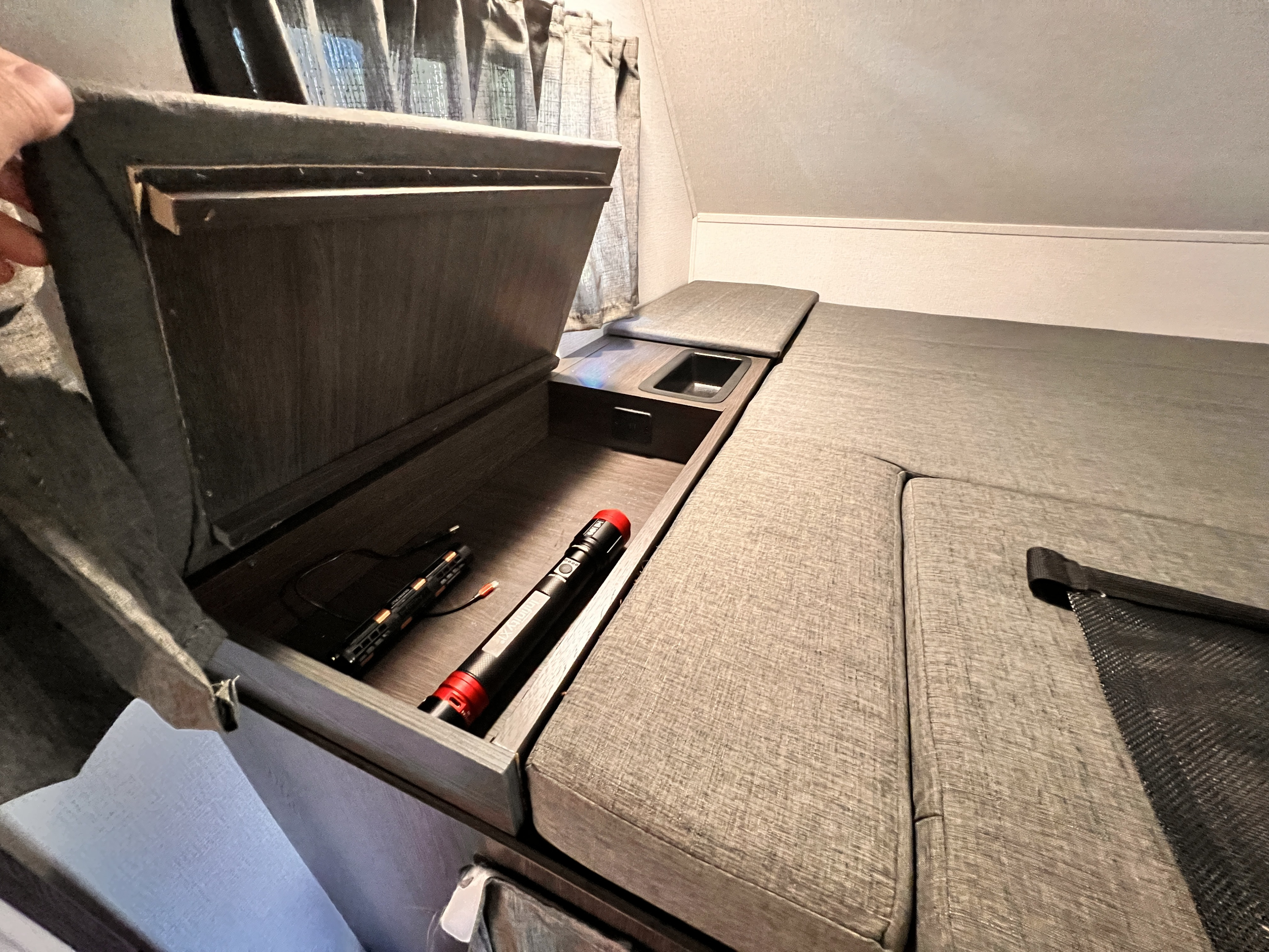 RV rental interior shows a comfy bed, handy open storage with charger and flashlight, plus a small integrated sink.. Forest River Sunseeker LE 2023