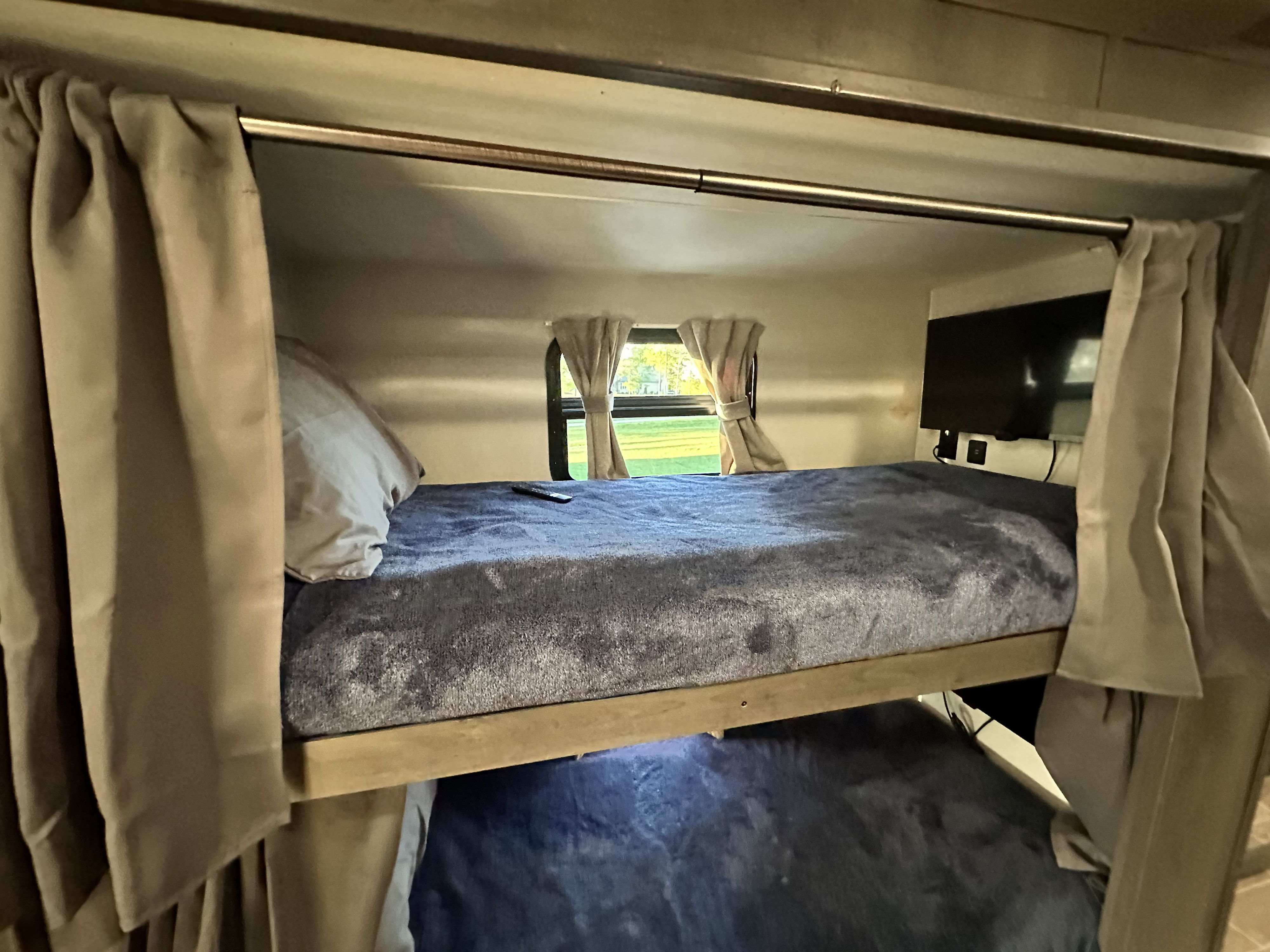 RV rental interior with cozy bunk beds, privacy curtains, a window view, and a wall-mounted TV.. Georgetown GT5 2021