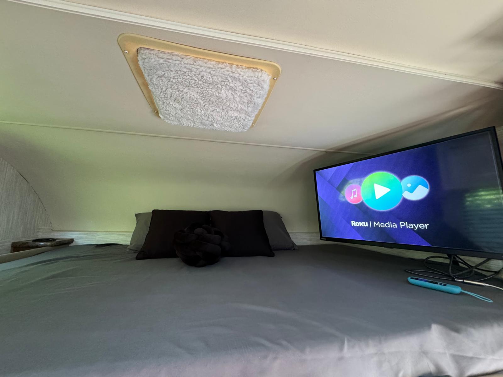 This RV rental offers a comfortable sleeping area with a Roku TV and a fluffy ceiling light fixture.. Thor Four Winds 2014