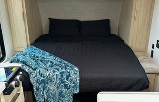 Cozy RV rental bedroom with dark bedding and a blue patterned throw blanket.. Forest River Salem FSX 2023