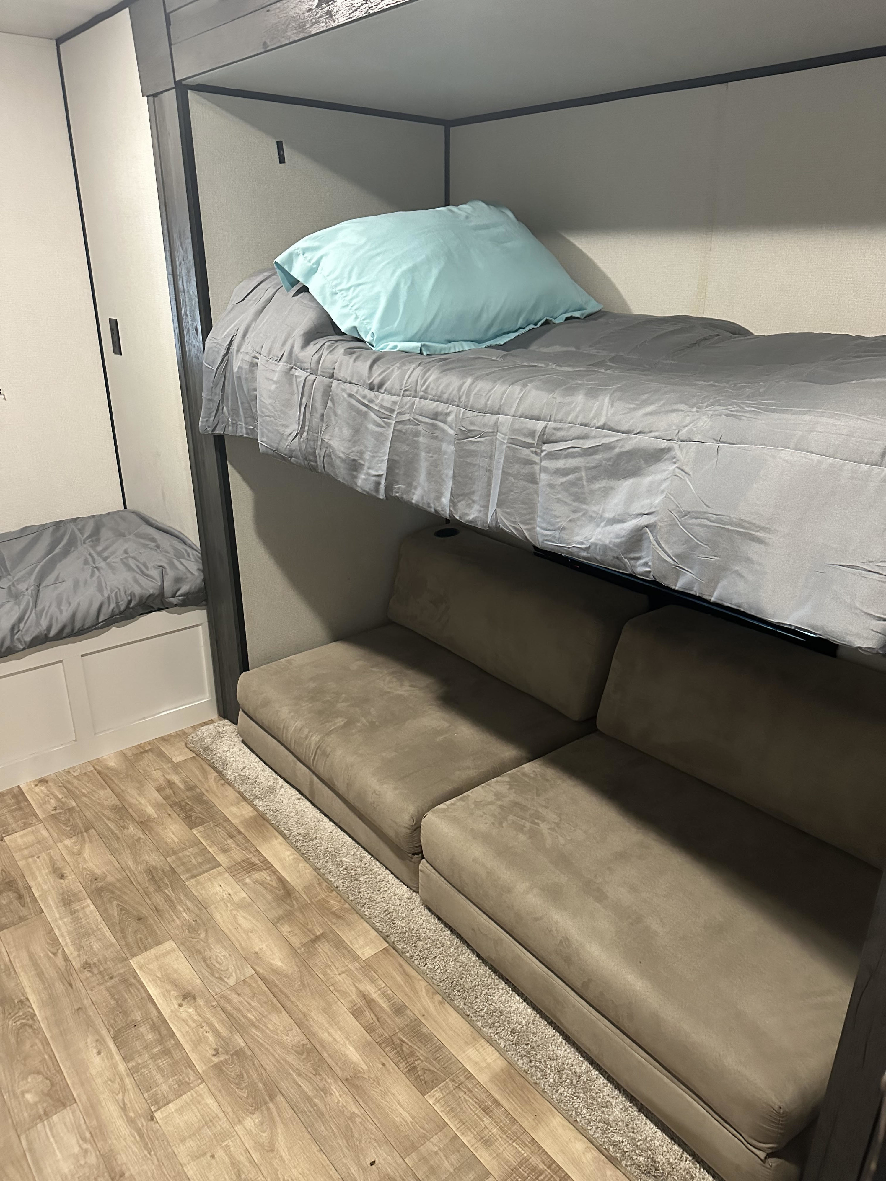 RV rental: a bunk bed with a blue pillow over modular seating, plus a bench on the left.. Keystone Hideout 2022