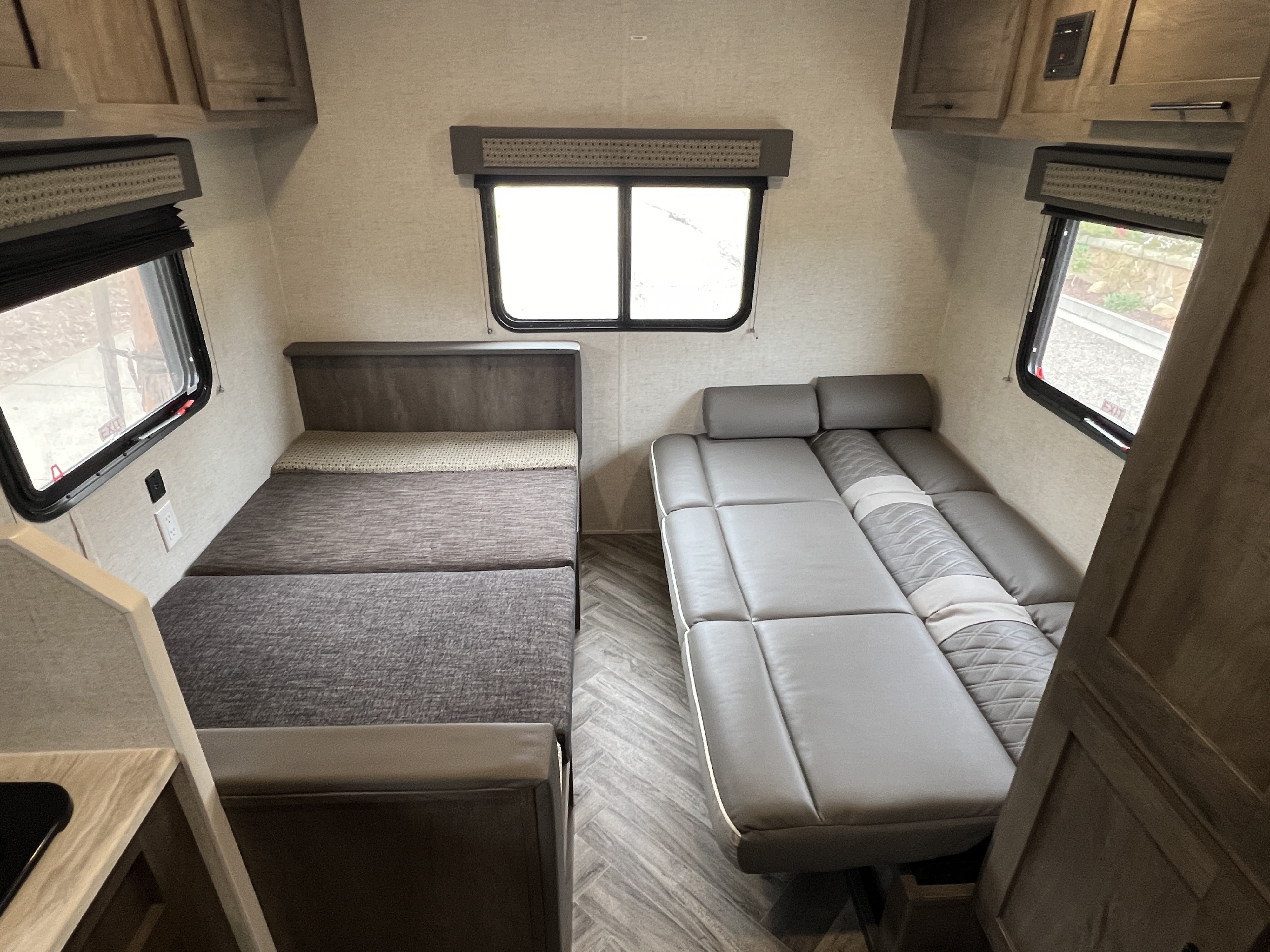 Inside an RV rental: versatile seating converts to beds on both sides, with windows and overhead storage for a cozy travel space.. Forest River EVO 208RD 2021