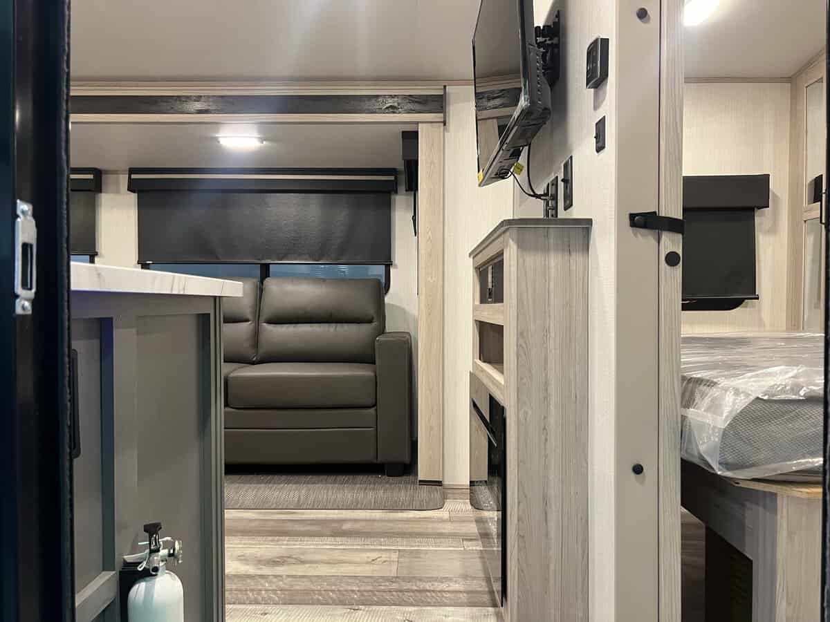 Modern RV rental interior with comfortable sofa, kitchen counter, entertainment unit, and bedroom. Ready for your adventure.. Heartland Sundance 2024