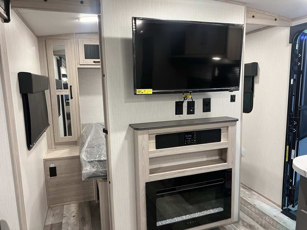 This modern RV rental offers a TV, entertainment system, and electric fireplace, with a cozy bedroom area.. Heartland Sundance 2024