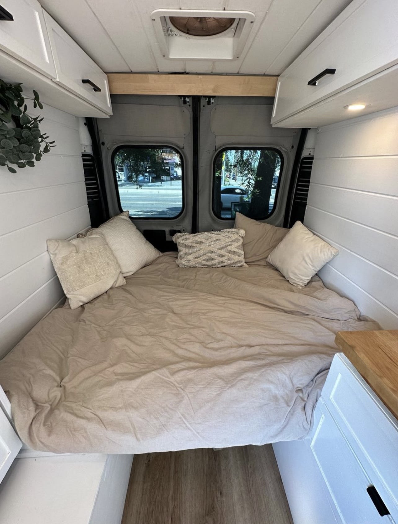 Modern RV rental: a cozy camper van bedroom with large bed, white shiplap walls, overhead storage, and rear windows.. Dodge Ram 1500 2015