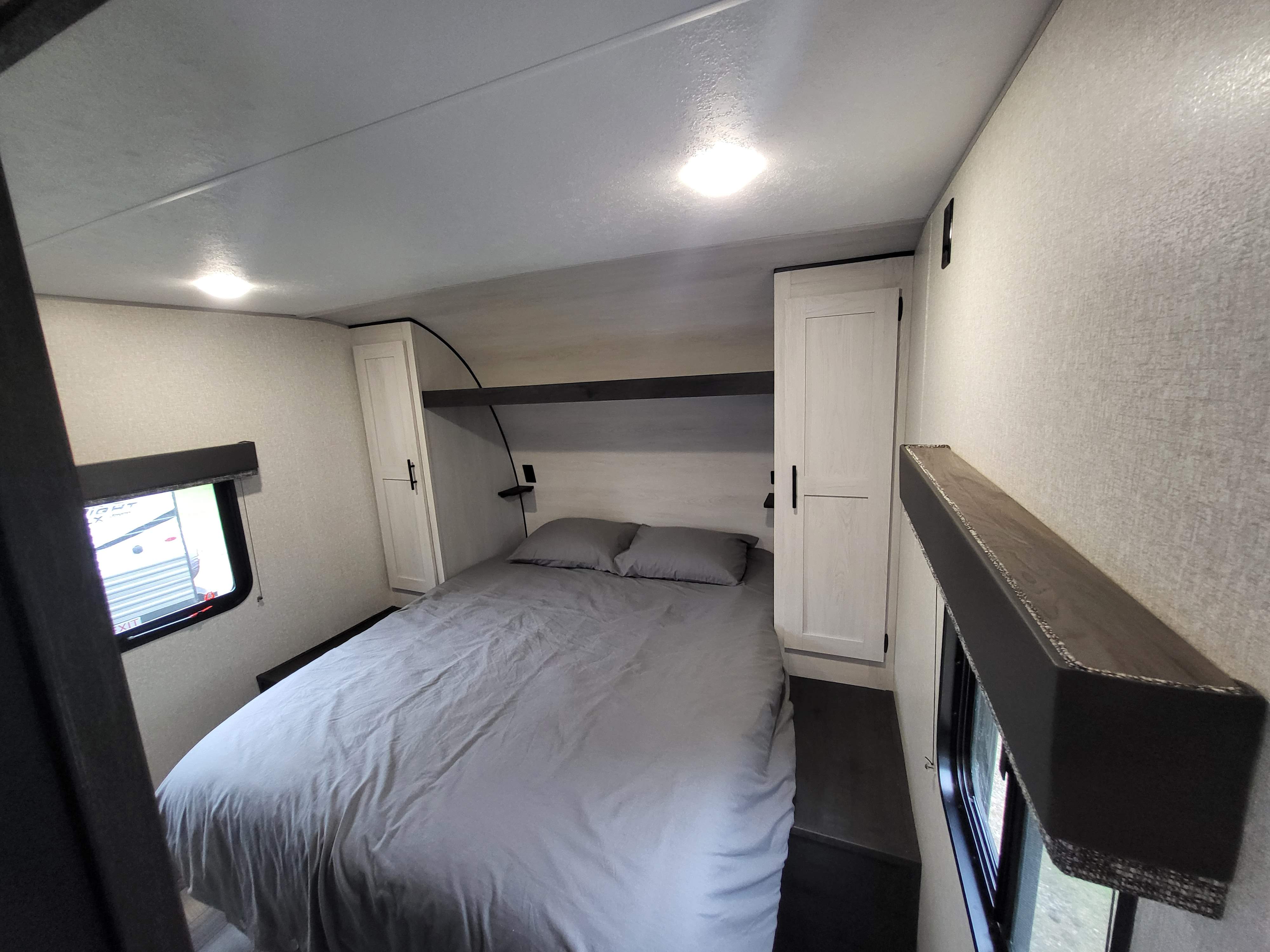 Inside an RV rental bedroom: a cozy space with a bed, built-in storage, window, and ceiling lights, ready for your trip.. Sportsmen SE 2022