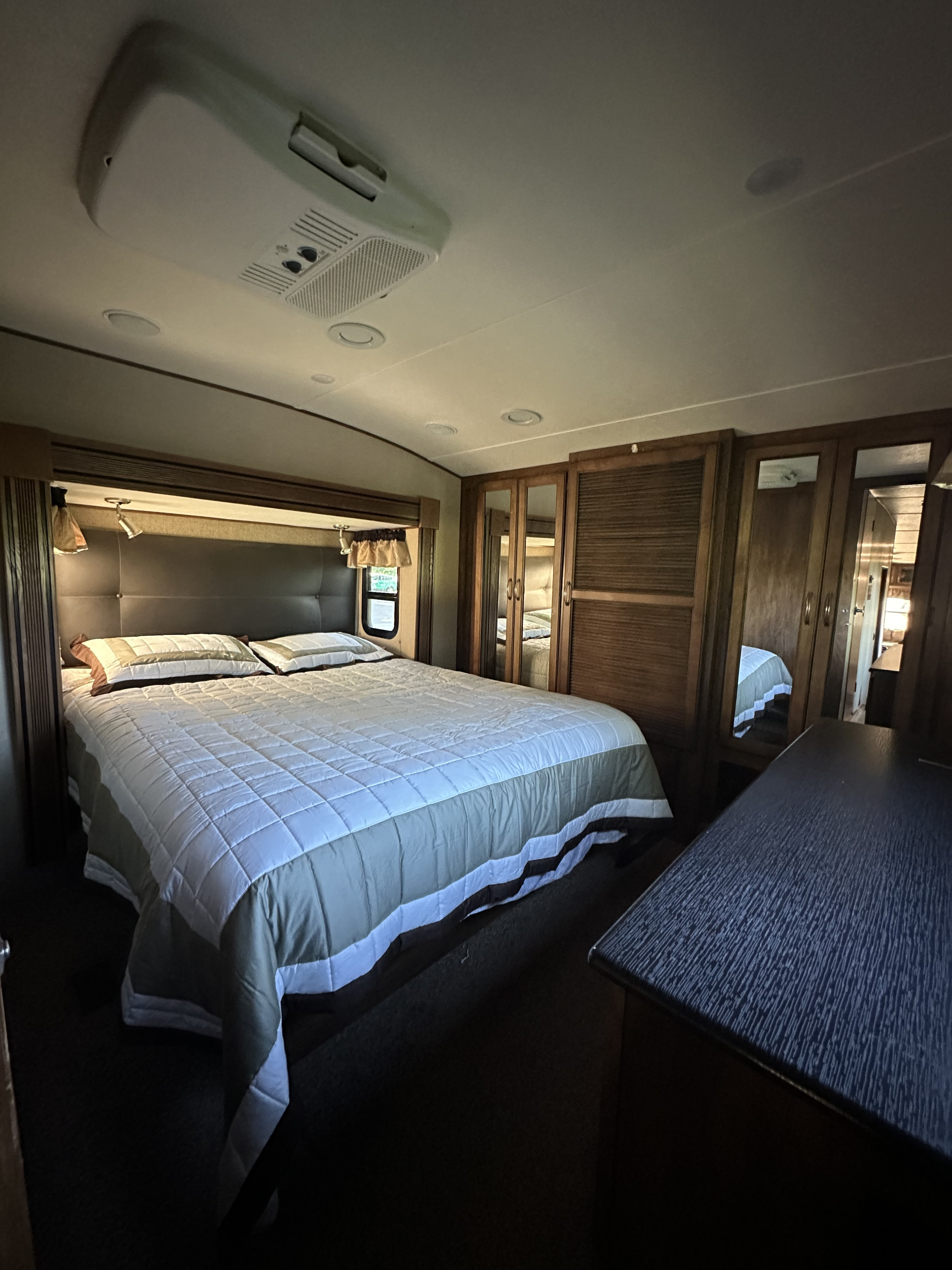 Spacious RV rental bedroom with a comfortable bed, mirrored wardrobes, and an AC unit, perfect for your next trip.. Forest River Coachmen Chapparal 2016