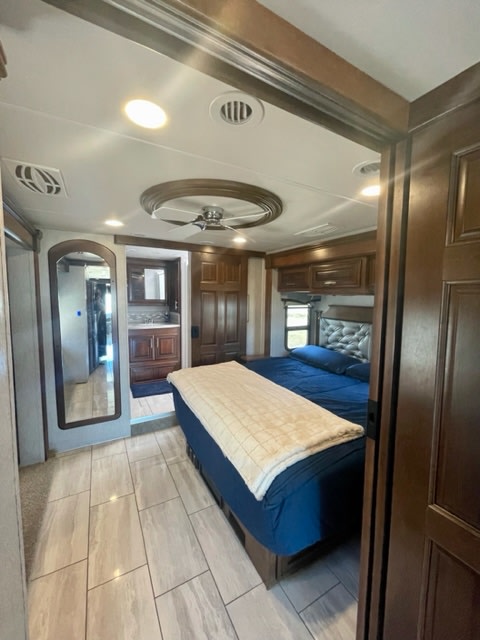 Spacious RV rental bedroom with modern decor, comfy bed, and a glimpse of the bathroom. Perfect home on wheels!. Forest River Berkshire 2021