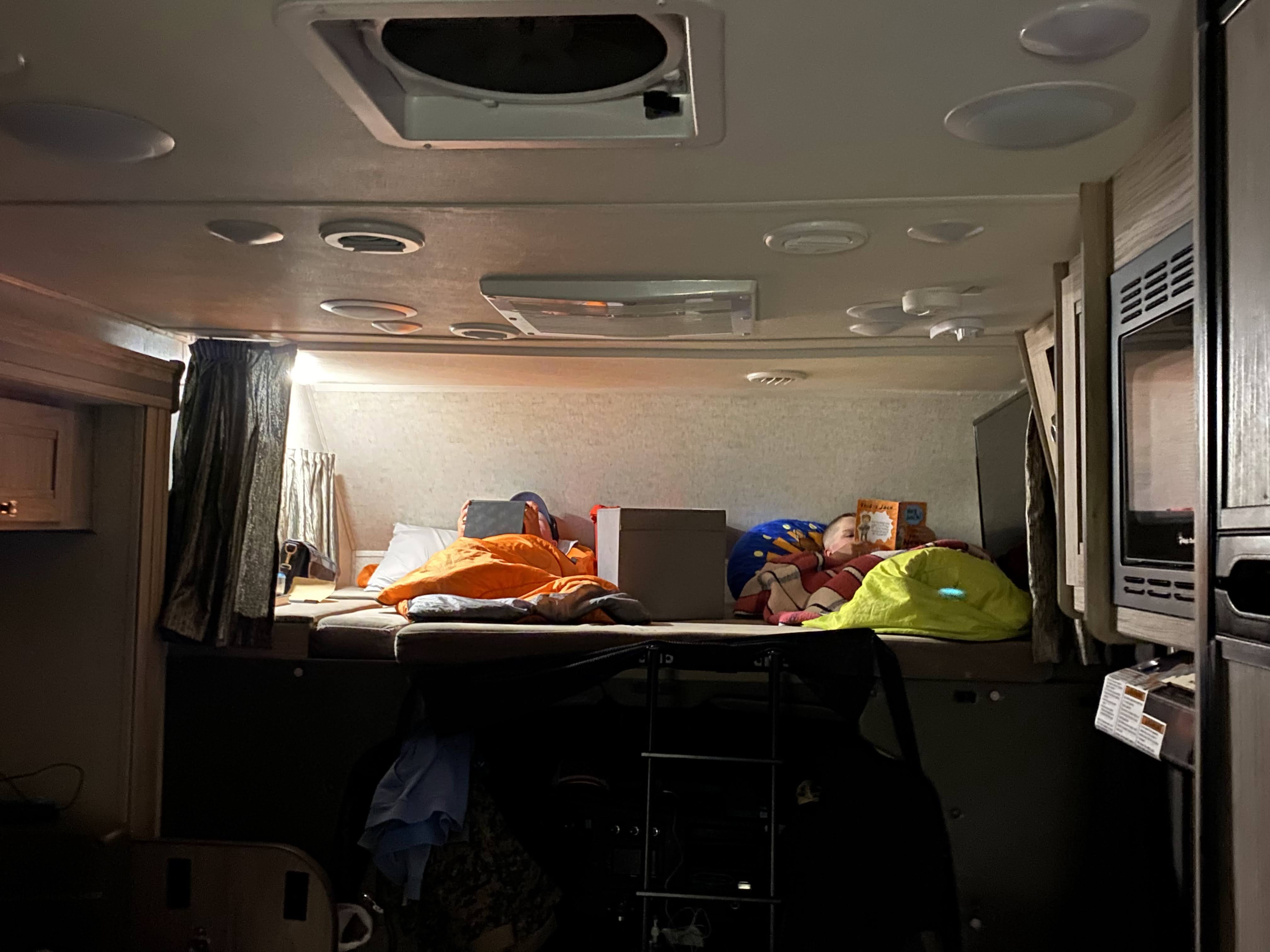 Cozy RV rental interior shows children resting in bunk beds, ideal for family travel and adventure.. Forest River Sunseeker 2018